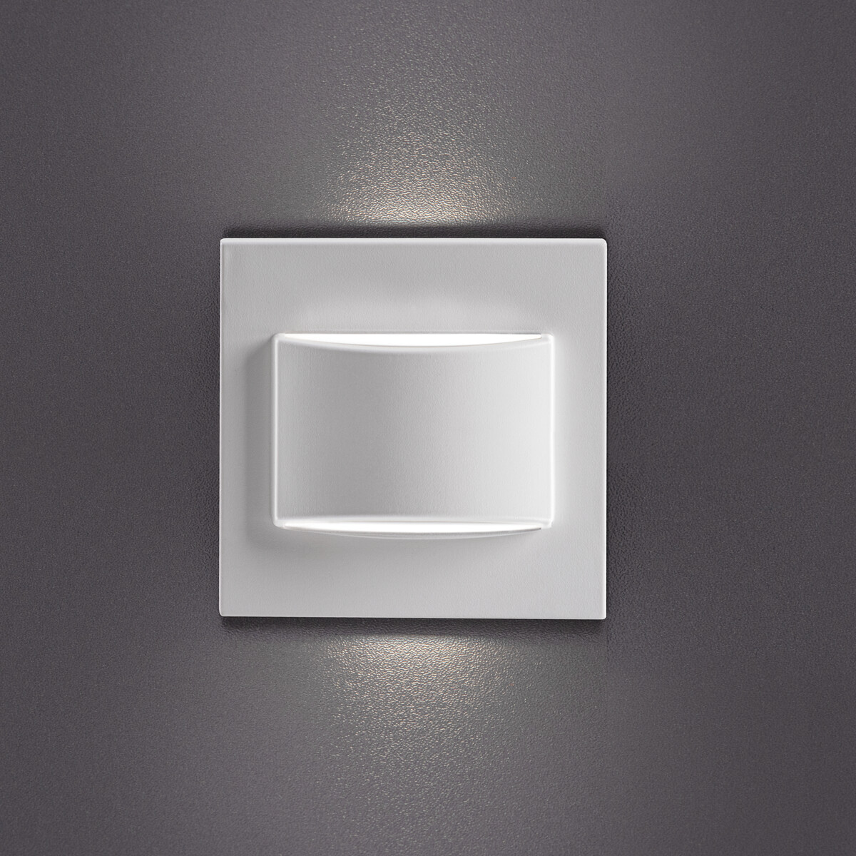 Aplique de pared blanco y cuadrado, con una fuente de luz empotrada y curva, montado en una pared gris.