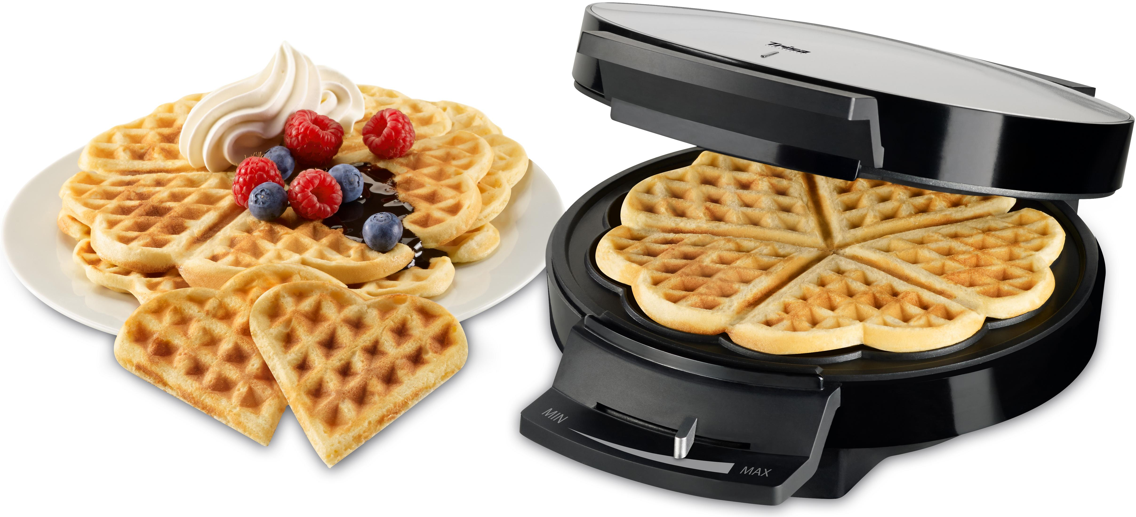 Herzförmige Waffeln mit Schlagsahne, Blaubeeren und Himbeeren. Waffeleisen rechts.