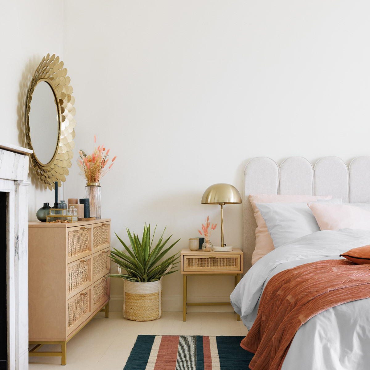 Ein Schlafzimmer mit Bett, Nachttisch, Spiegel und Kommode. Neutrale Farben.