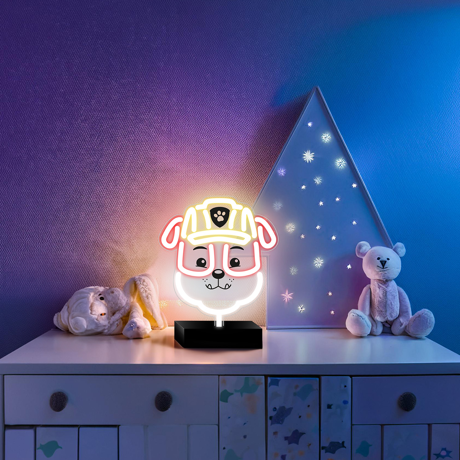 Neonowa lampa w kształcie psa na komodzie, inne zabawki i lampa w kształcie choinki. Fioletowe i niebieskie ściany.