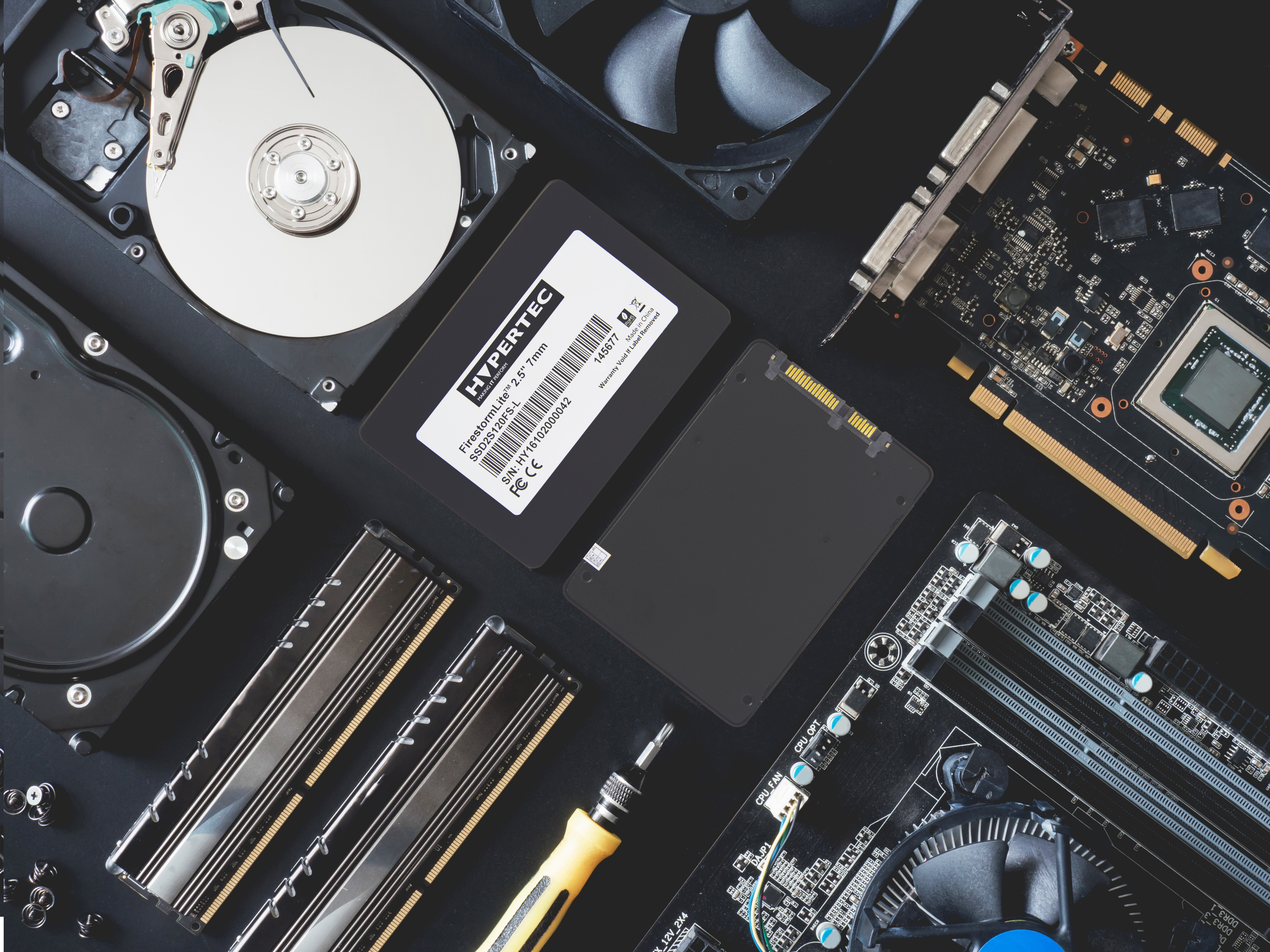 Componenti del computer su una superficie nera. Include SSD, RAM e altre parti.