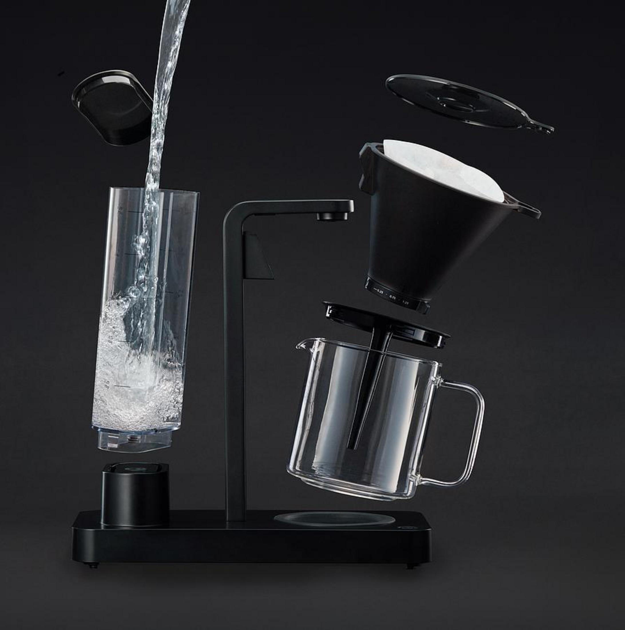 Macchina per caffè in vista esplosa. Versamento d'acqua, componenti separati su sfondo nero.