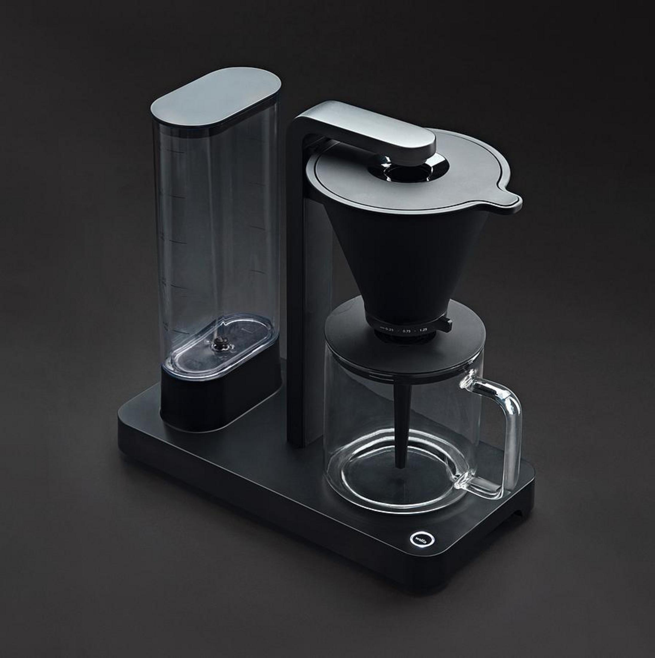 Macchina da caffè con serbatoio dell'acqua, filtro e caraffa in vetro. Sfondo scuro.