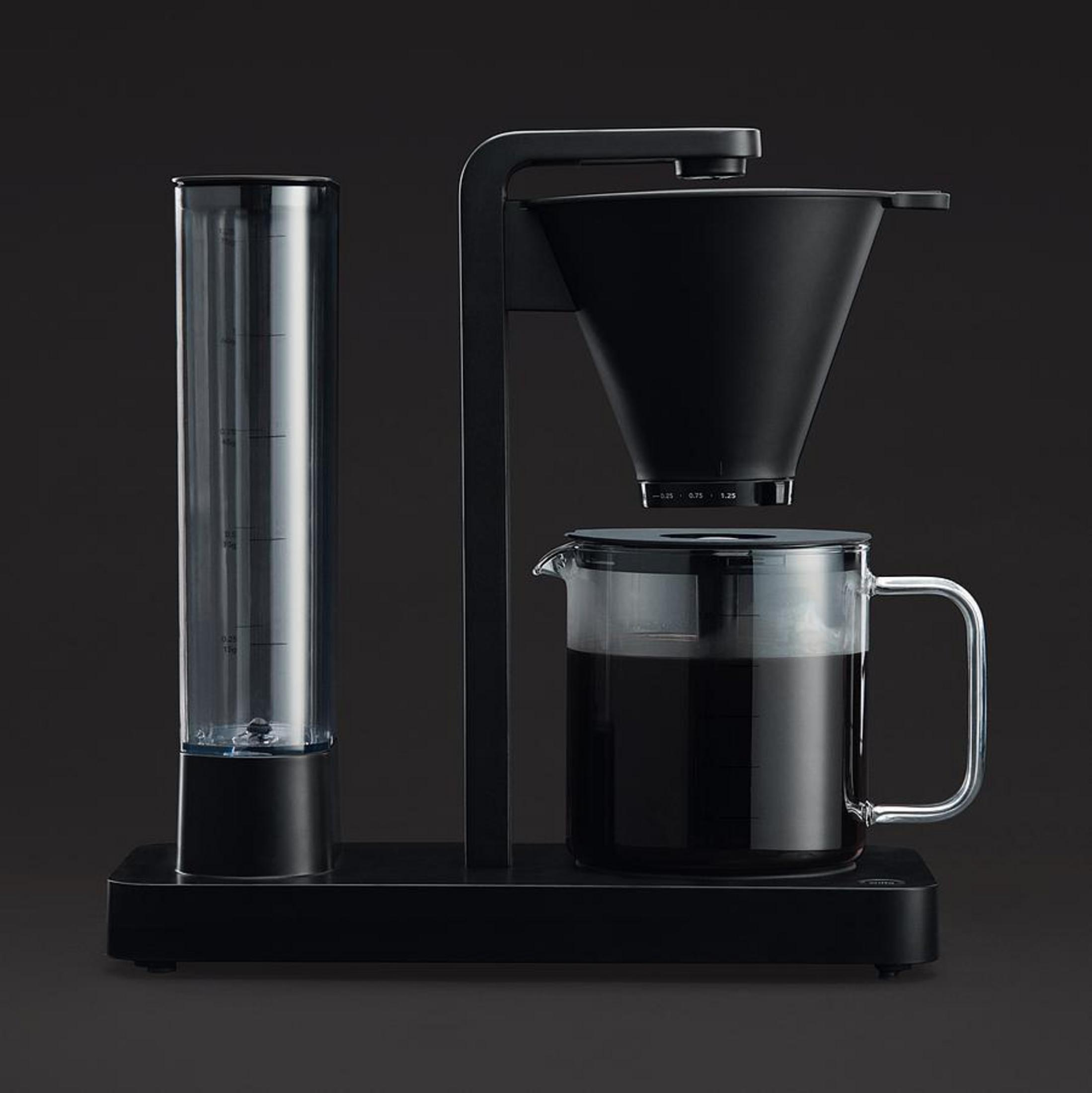 Macchina da caffè nera con serbatoio dell'acqua, filtro a cono e caraffa in vetro piena di caffè.