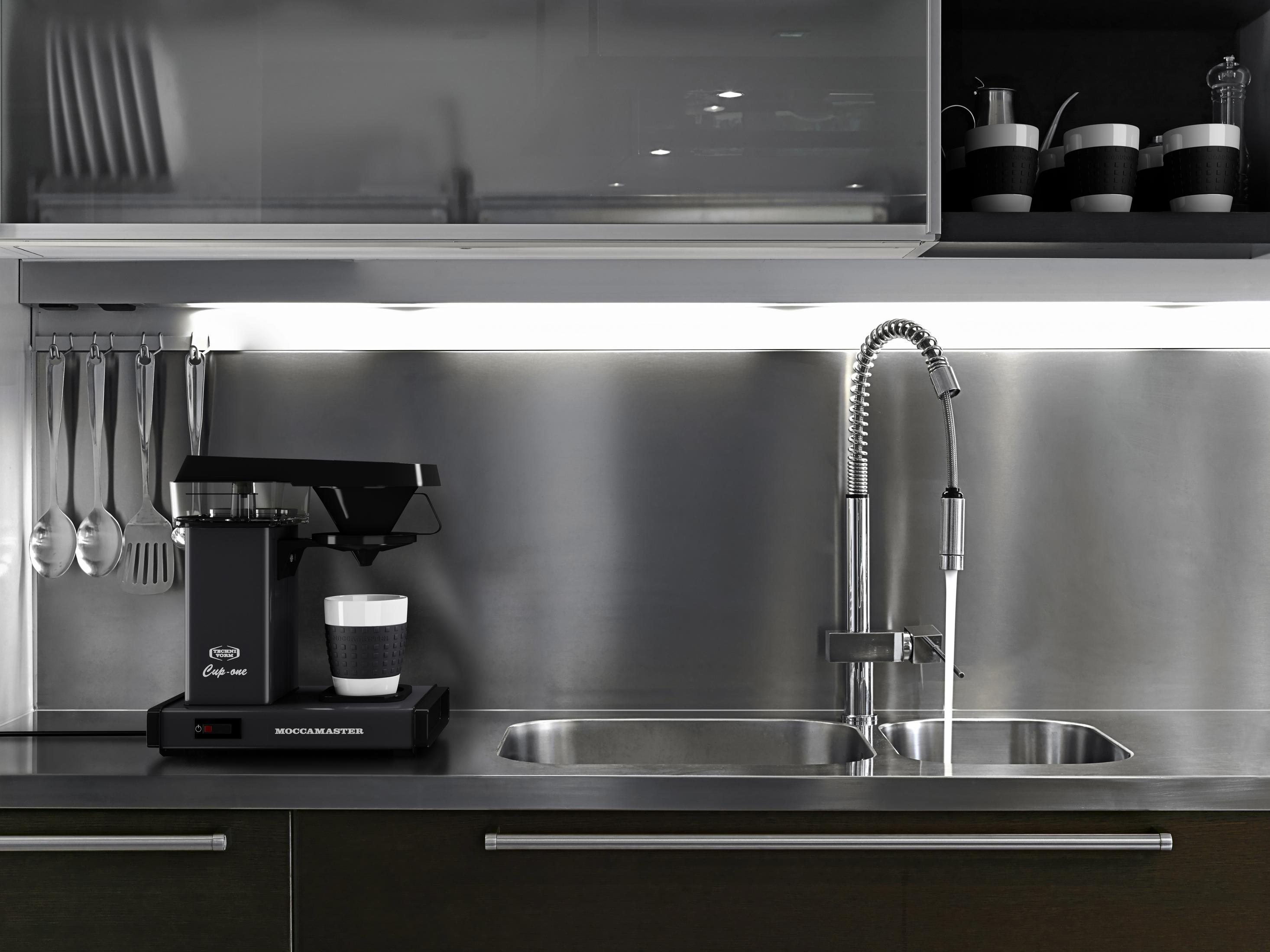 A kitchen counter with a coffee maker, sink, and hanging utensils.