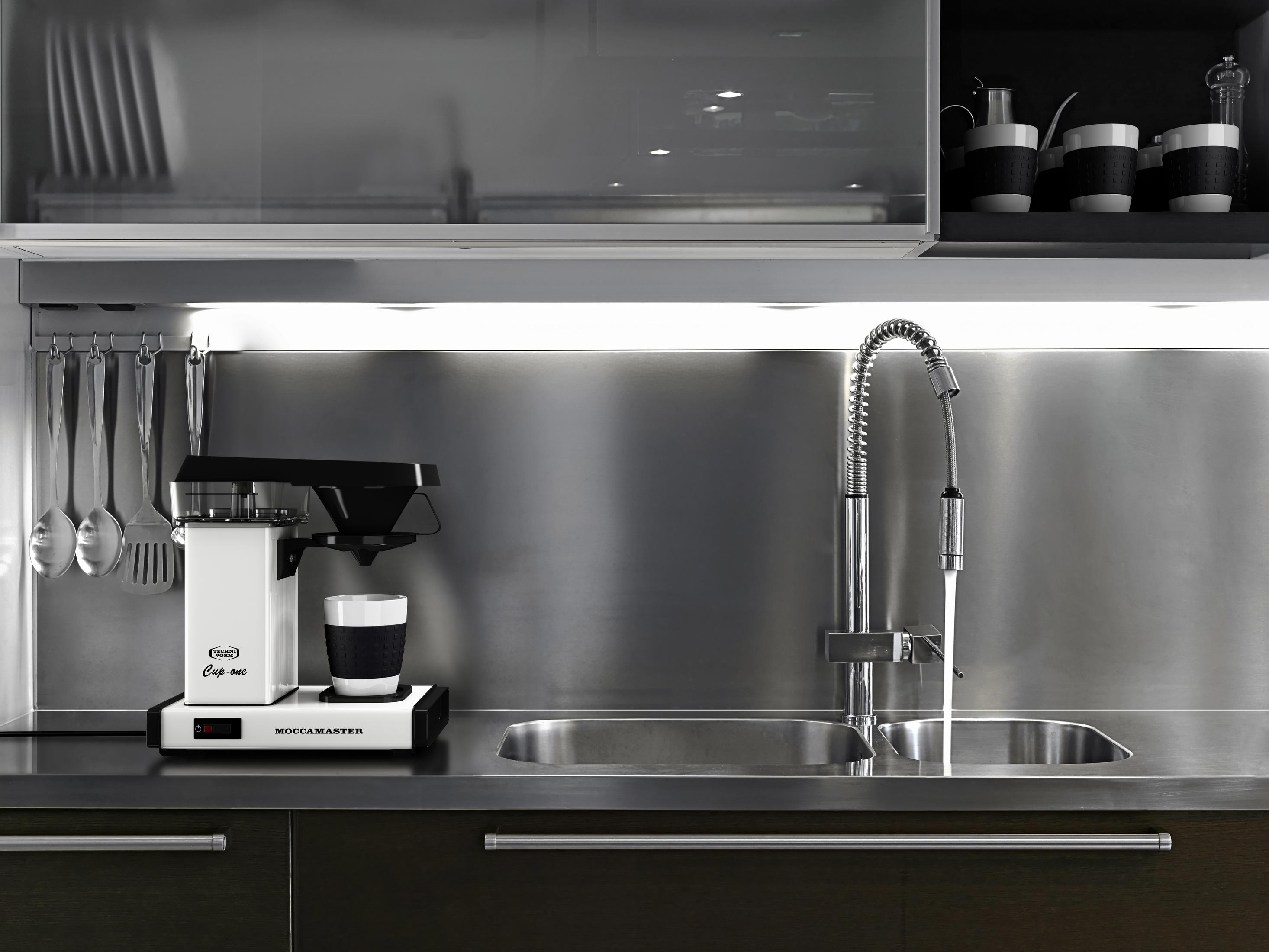 Küchentheke mit einer weißen Moccamaster Kaffeemaschine, Spüle und Wasserhahn.