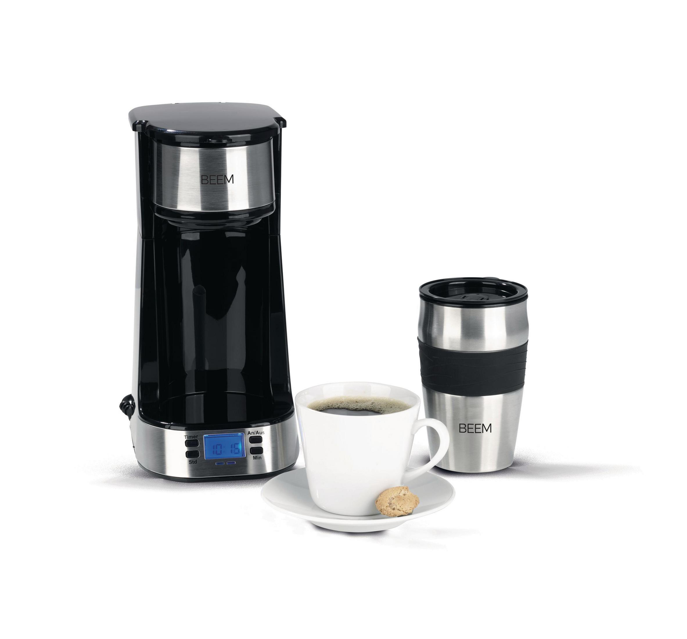 Schwarz-silberne Kaffeemaschine, Tasse, Untertasse, Keks und Thermobecher. Alles auf weißem Grund. Die Szene ist aufgebaut.