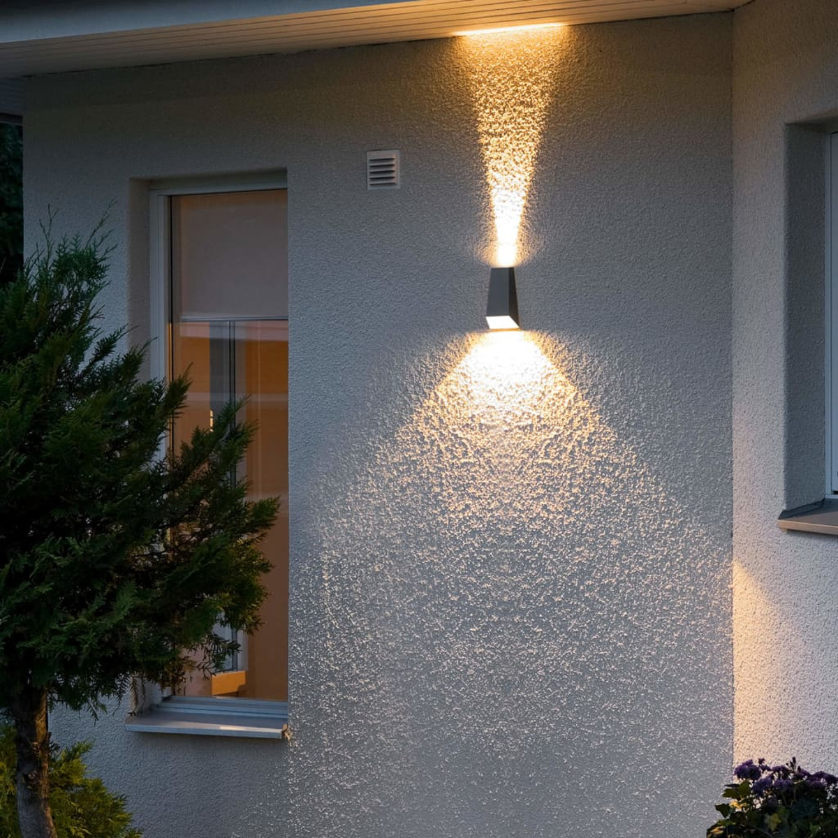 Wandleuchte mit Licht nach oben und unten, an einer strukturierten Wand.