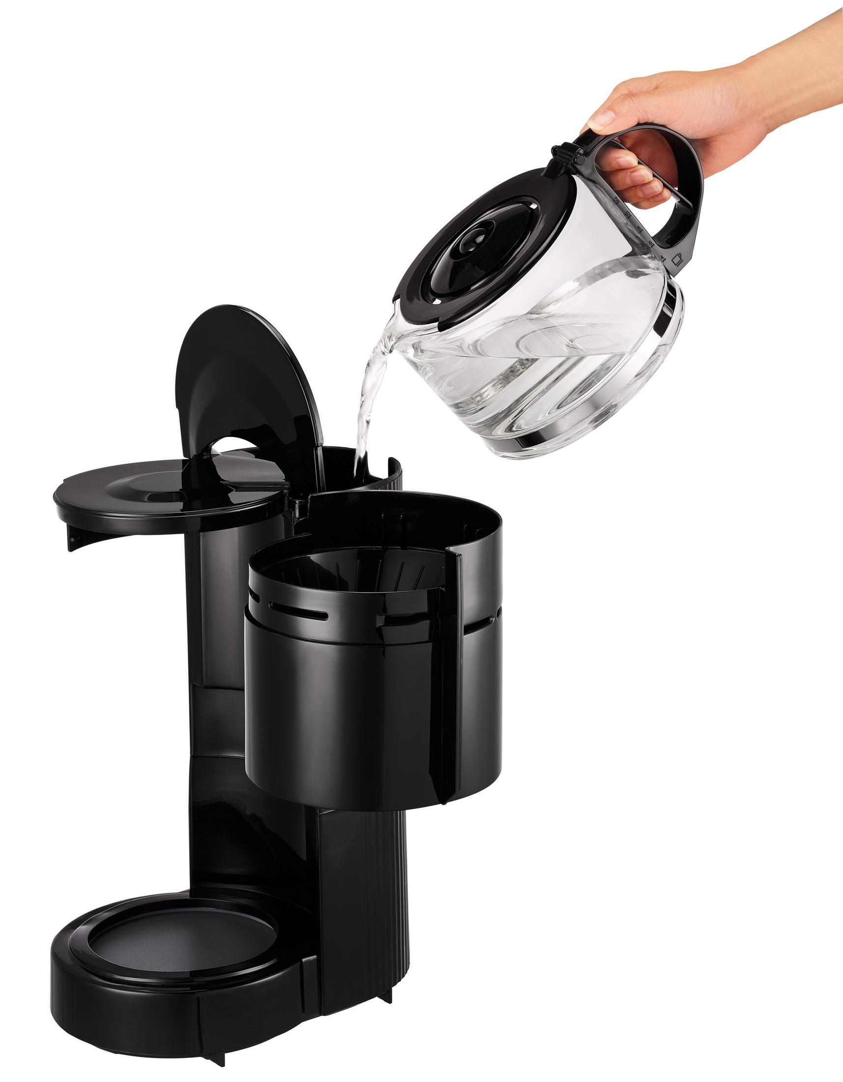 Hand gießt Wasser in eine schwarze Kaffeemaschine. Die Karaffe ist klar.