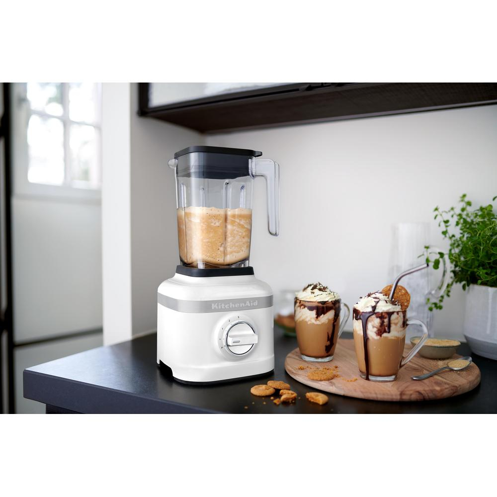 Frullatore KitchenAid bianco con caraffa trasparente, coperchio nero e pannello di controllo argentato.