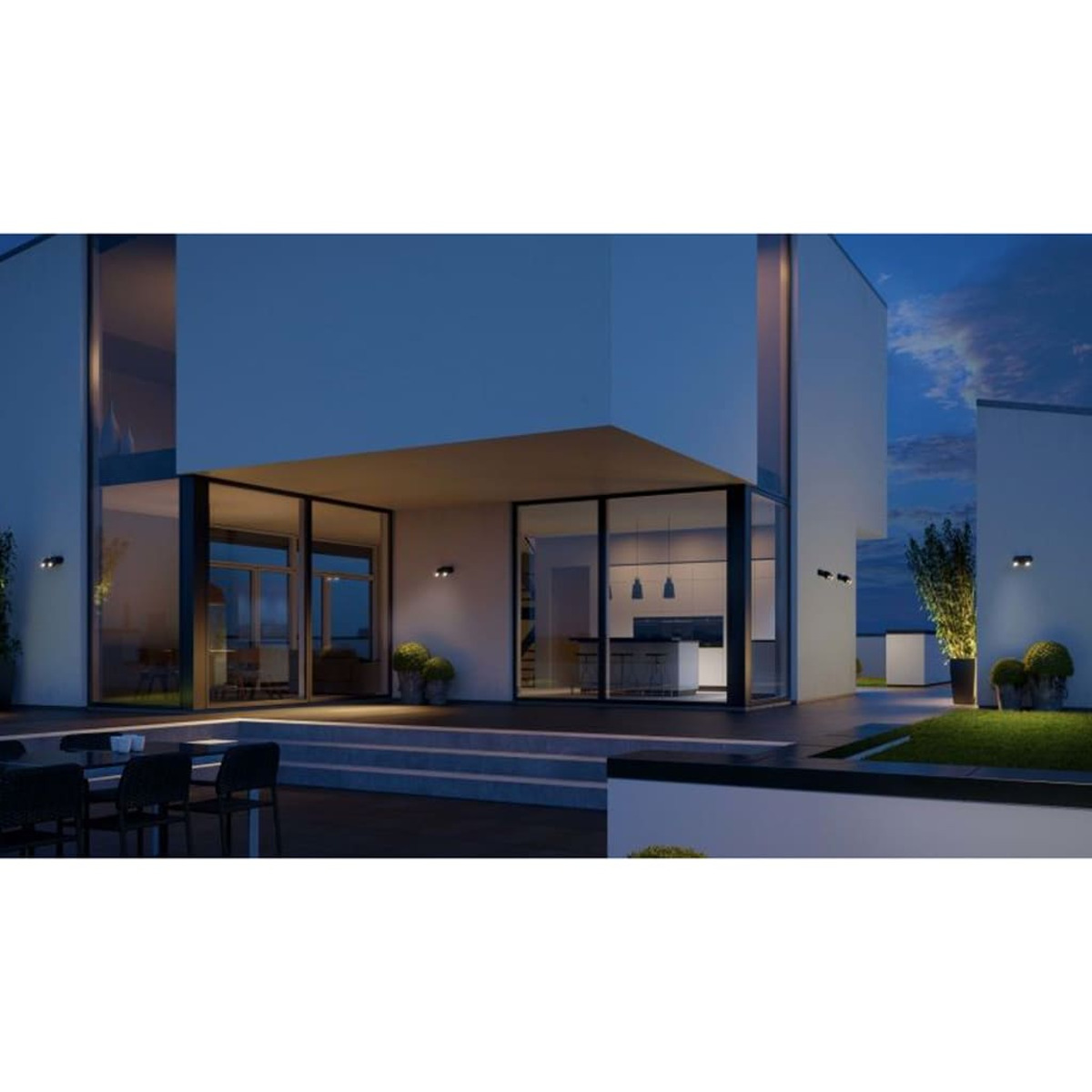 Zewnętrzny widok nowoczesnego budynku o zmierzchu, z zapalonymi światłami i dobrze oświetlonym patio.