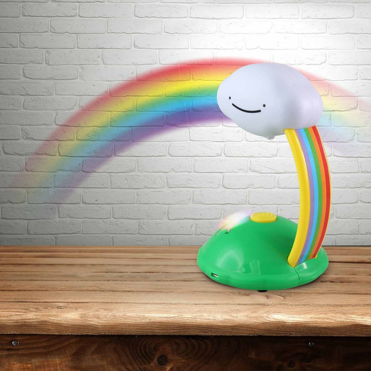 Wolkenförmige Lampe mit Regenbogenlichtprojektion auf einem Holztisch, Backsteinmauer im Hintergrund.