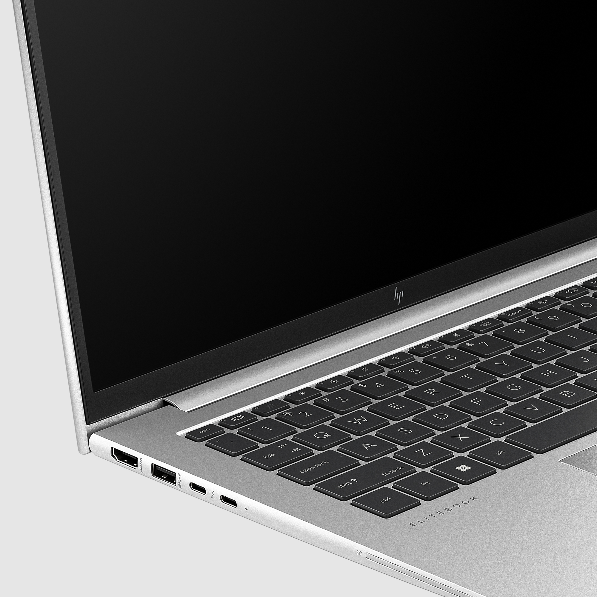 Zbliżenie klawiatury srebrnego laptopa. Czarne klawisze, białe litery i czarny ekran.