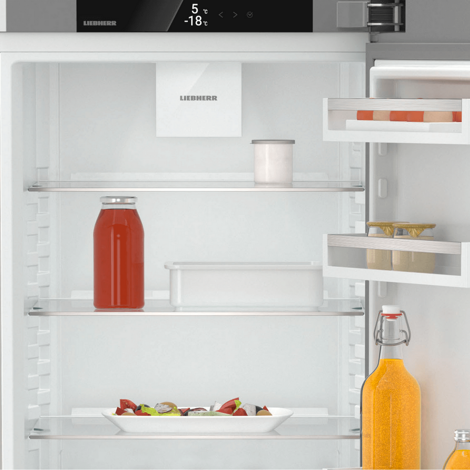 Interno del frigorifero Liebherr. Succo rosso, insalata e altri oggetti sui ripiani, pannello superiore.