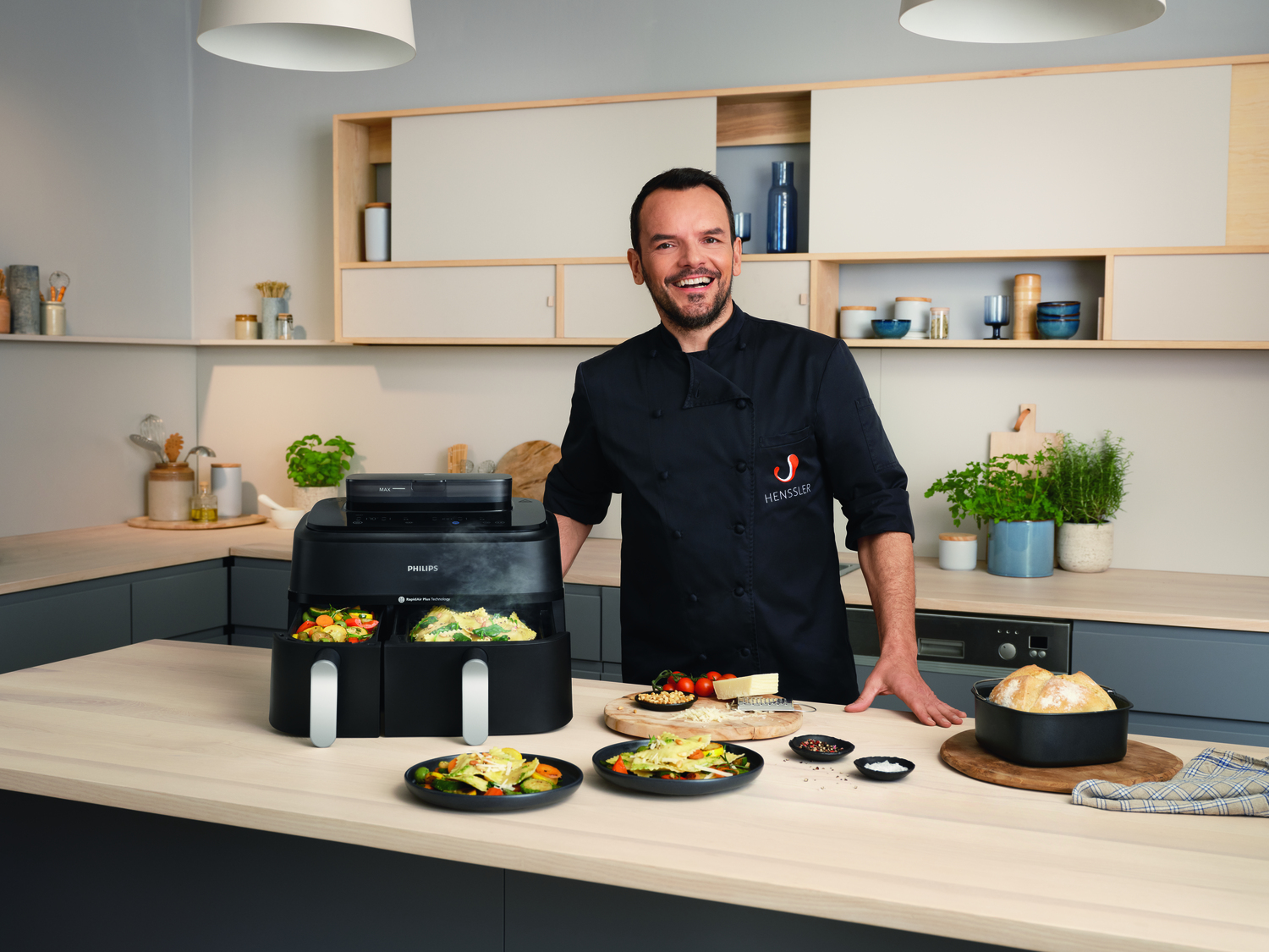 Een man in een chef-kok uniform in een keuken met een Philips airfryer.