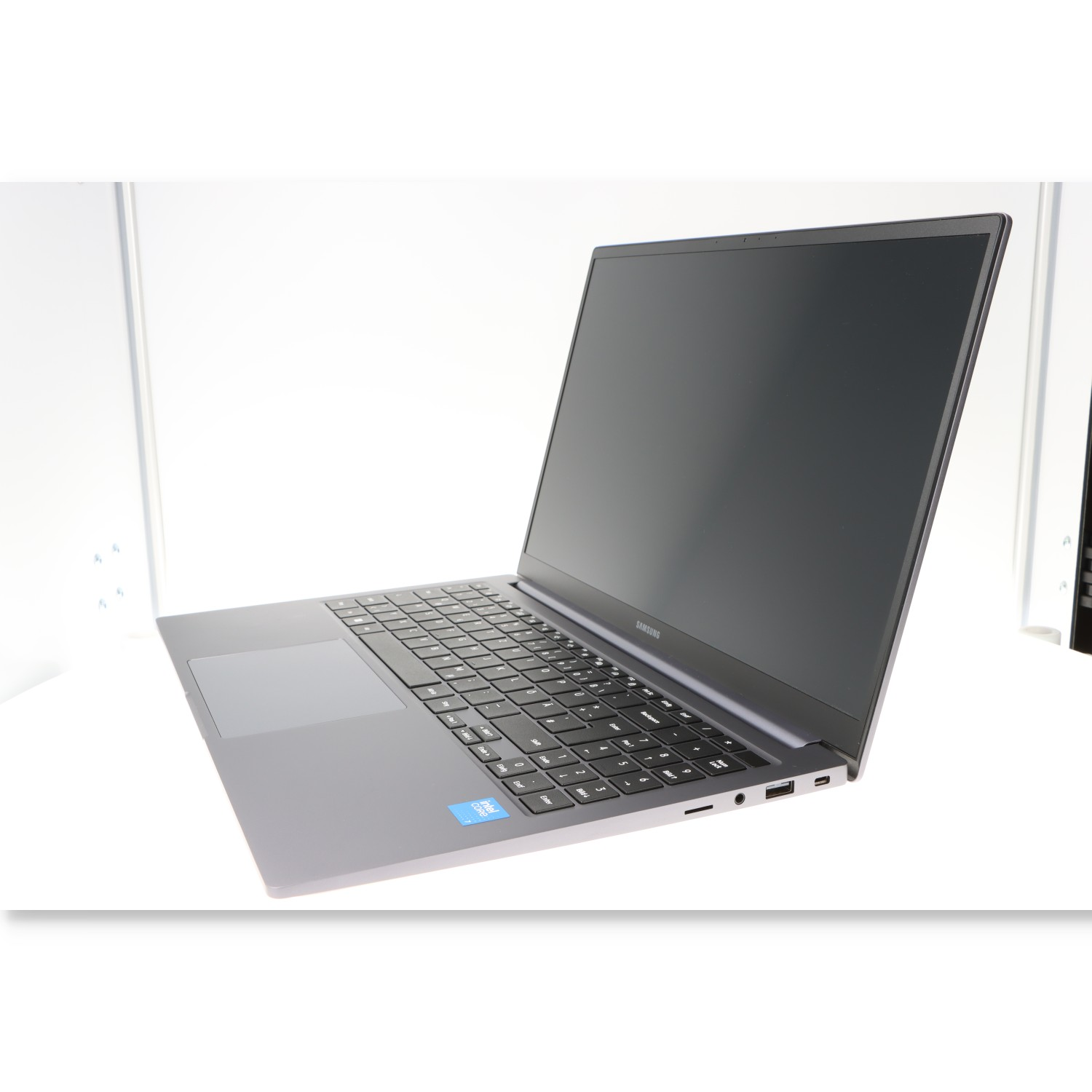 Laptop auf weißer Oberfläche. Grauer Laptop mit schwarzer Tastatur und Bildschirm. Der Bildschirm ist leer.
