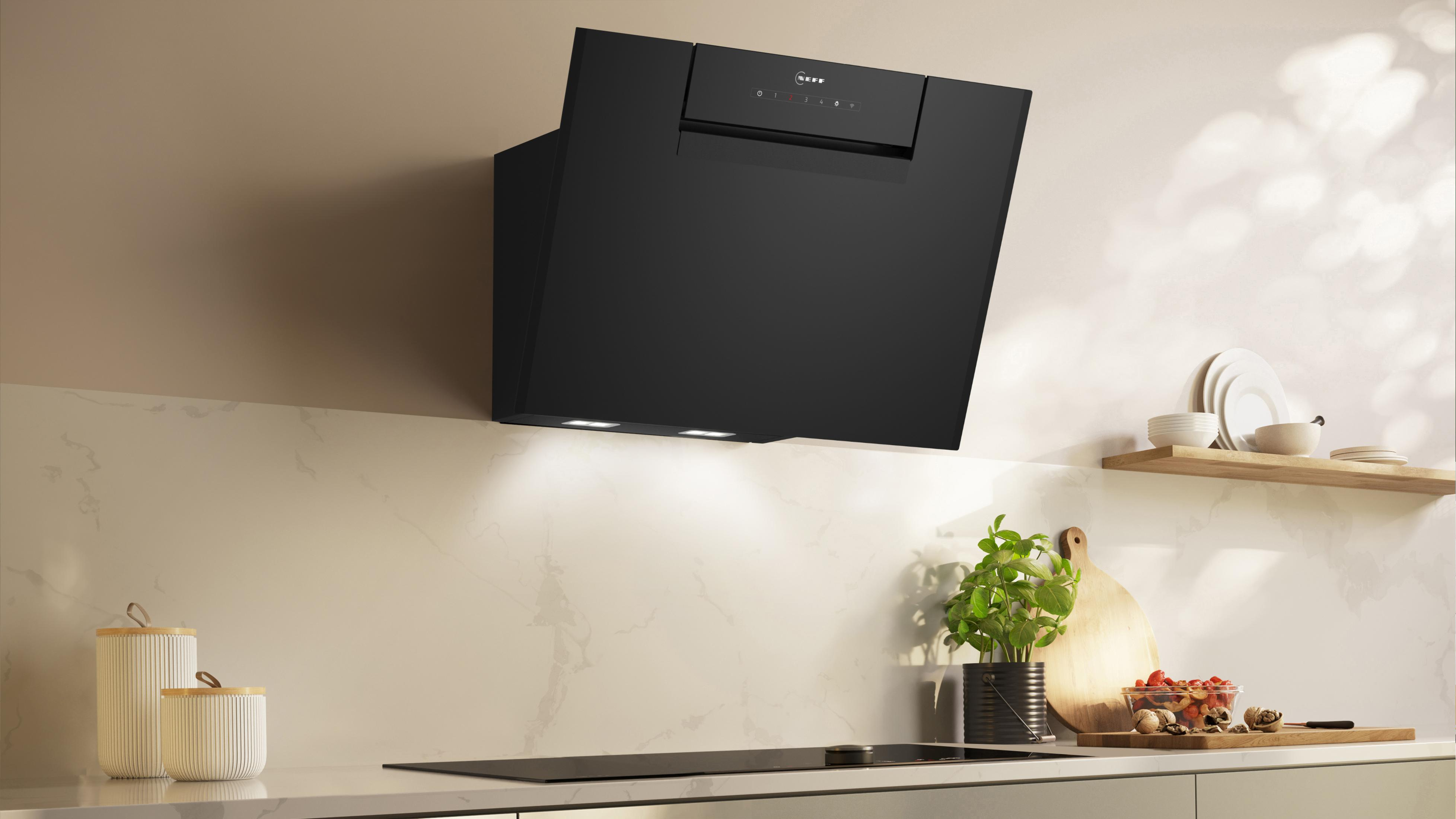 Una cappa da cucina nera installata su una parete bianca con una luce sopra un piano di lavoro.