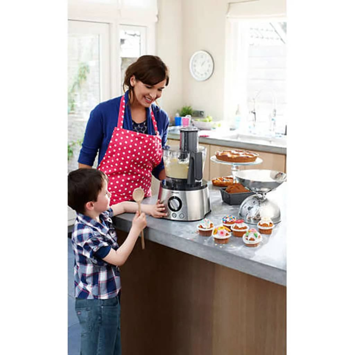 Kobieta i dziecko w kuchni. Kobieta używa robota kuchennego. Babeczki na blacie.