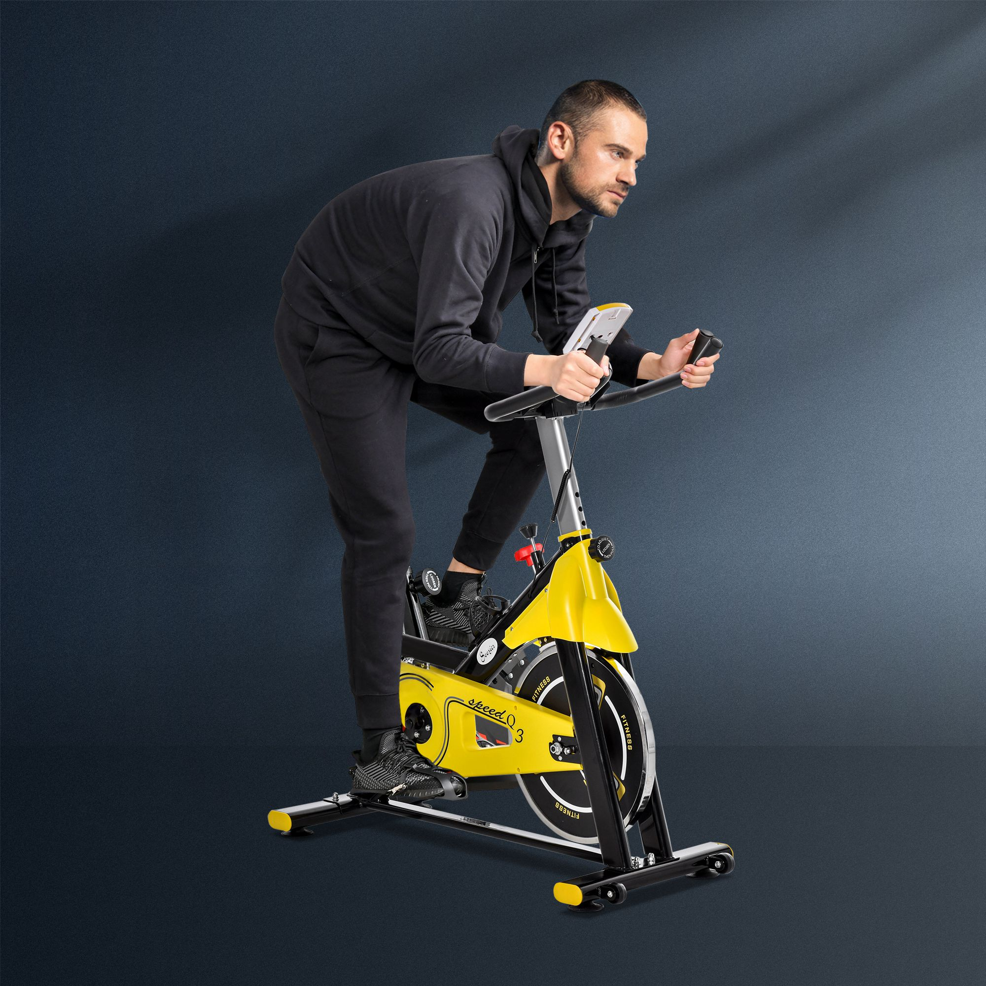 Mann auf gelbem Heimtrainer. Er trägt schwarze Sportkleidung und hat einen konzentrierten Gesichtsausdruck.