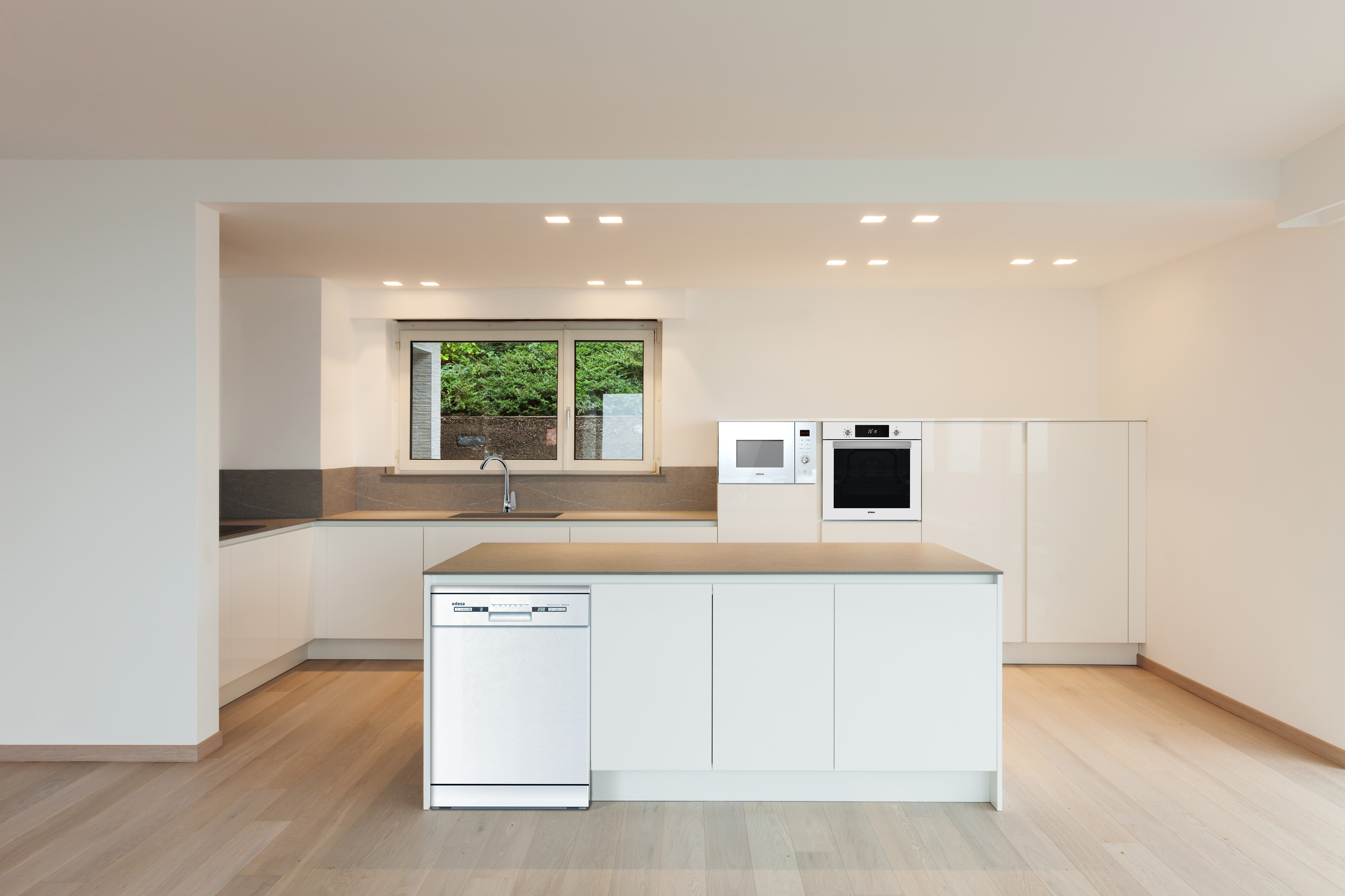 Cocina moderna con armarios blancos, isla y lavavajillas integrado. Suelo de madera y ventana.