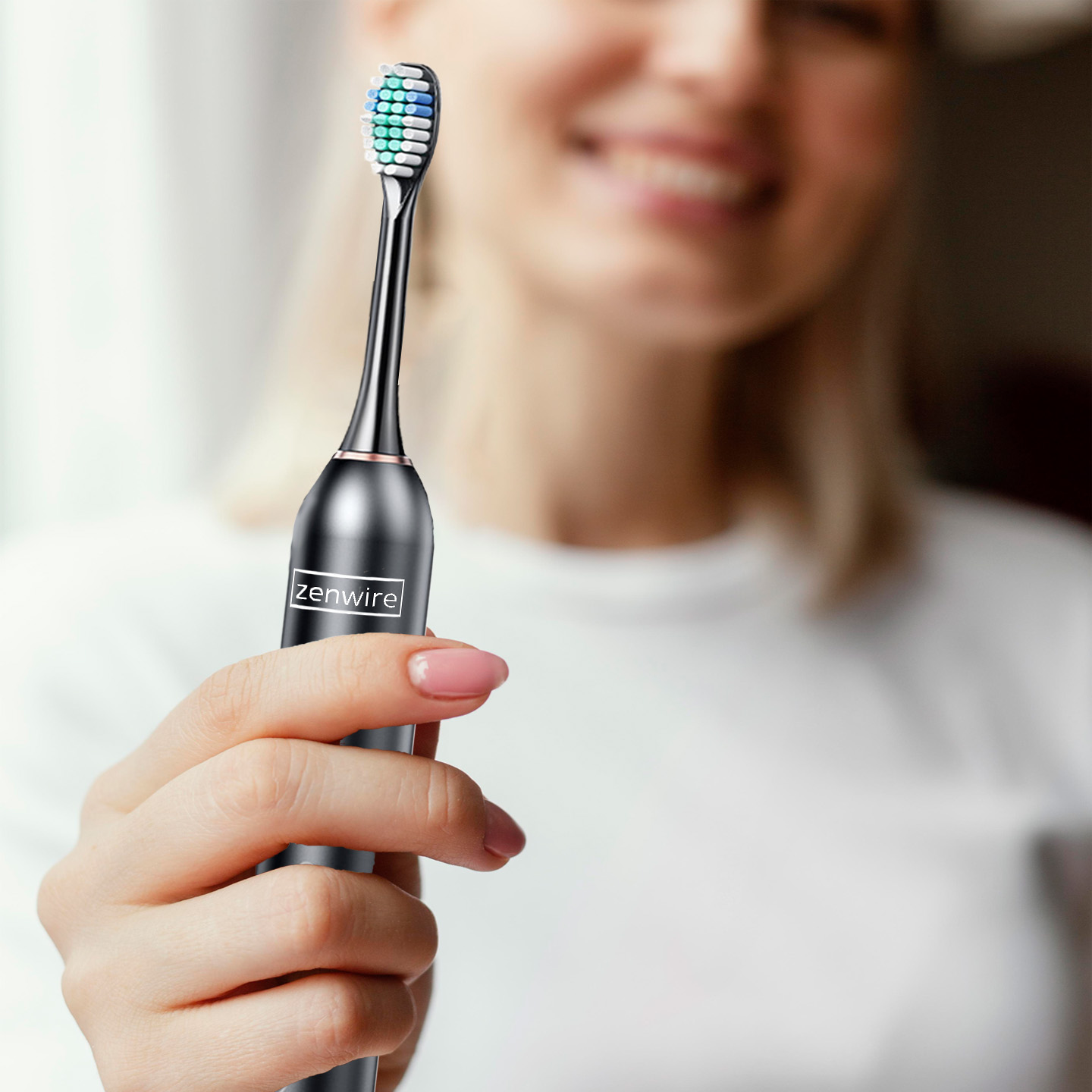 Kobieta trzymająca czarną i srebrną szczoteczkę do zębów. Szczoteczka ma niebiesko-zieloną główkę.
