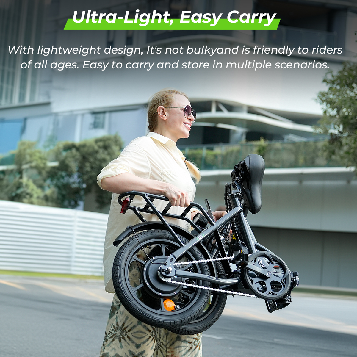 Kobieta trzyma złożony czarny rower elektryczny. Tekst: 'Ultra-Light, Easy Carry'. W tle budynki.