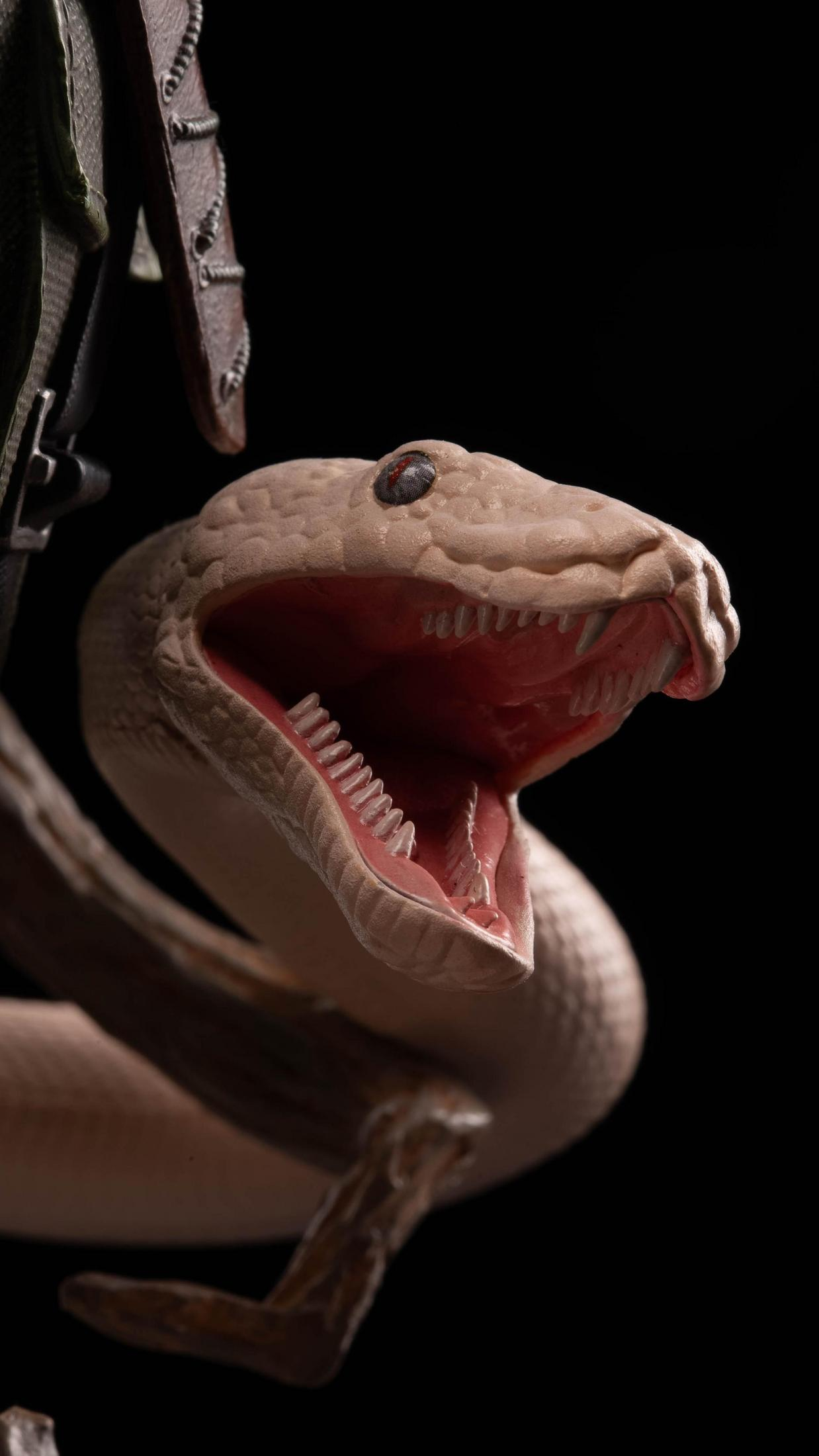 Głowa węża z otwartą paszczą, ukazująca zęby i czerwone wnętrze, na czarnym tle.