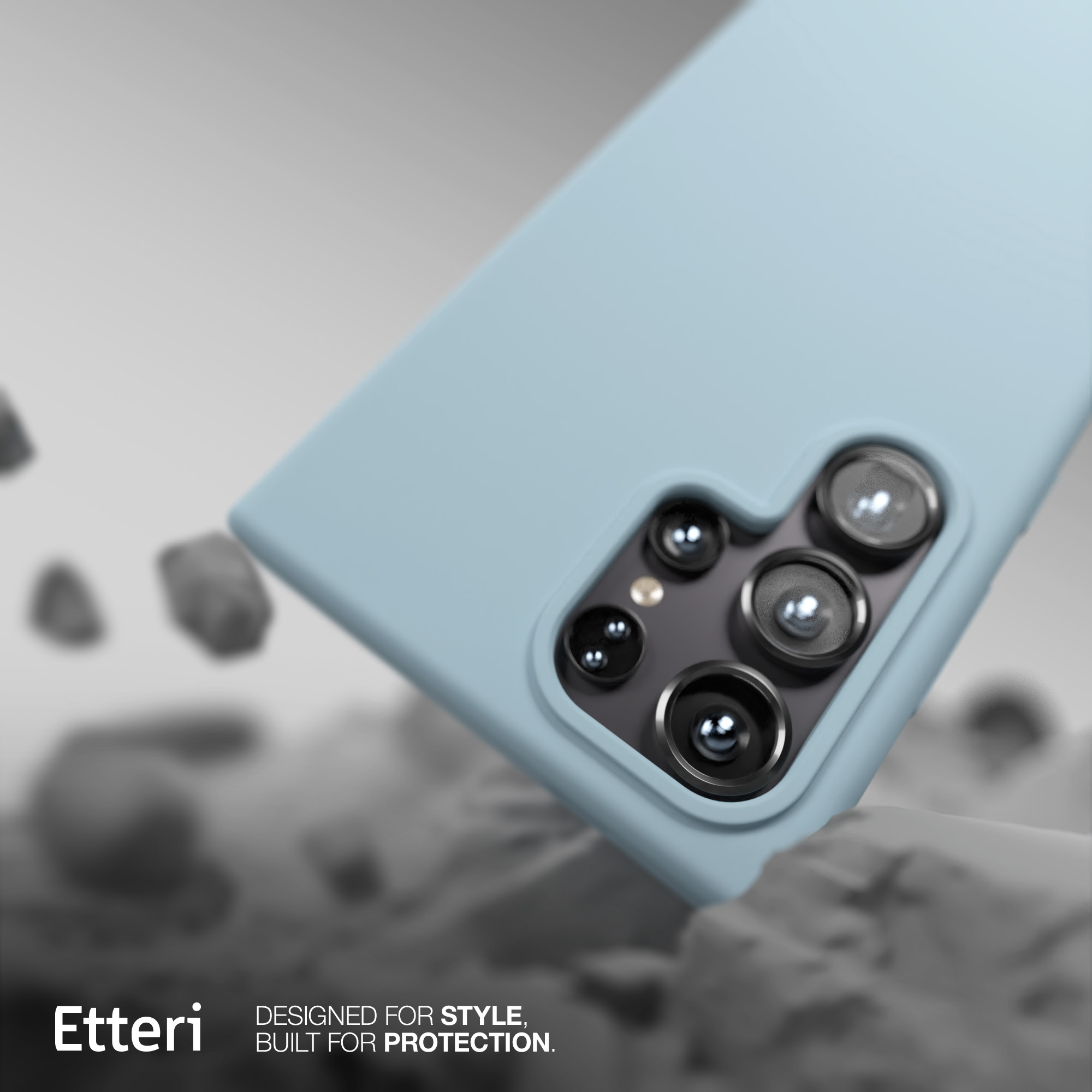 Custodia blu chiaro con lenti della fotocamera visibili, testo 'Etteri', su superficie rocciosa.