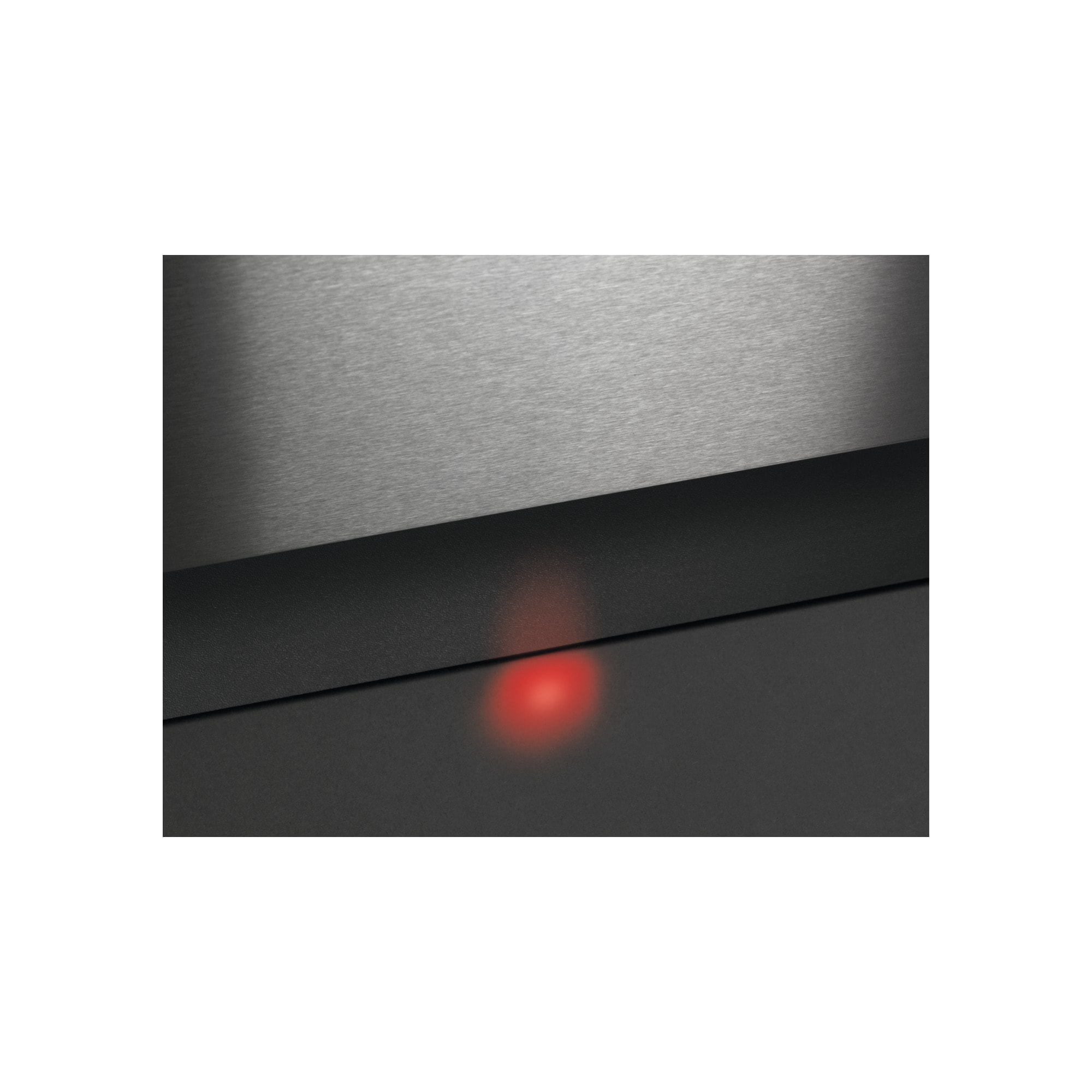 Zbliżenie metalowej powierzchni z czerwonym światłem. Powierzchnia jest czarna u dołu.