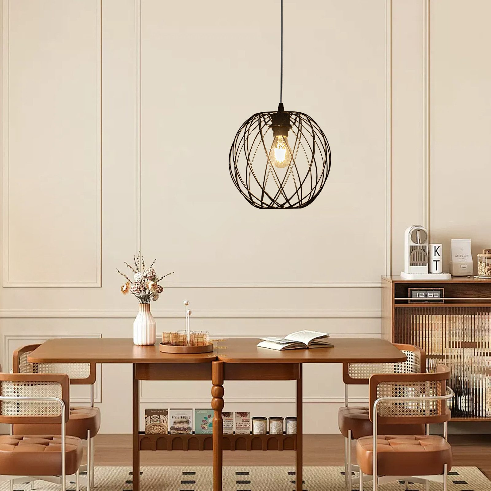 Sala da pranzo con tavolo, sedie e lampada a sospensione. La lampada è una gabbia nera con una lampadina.