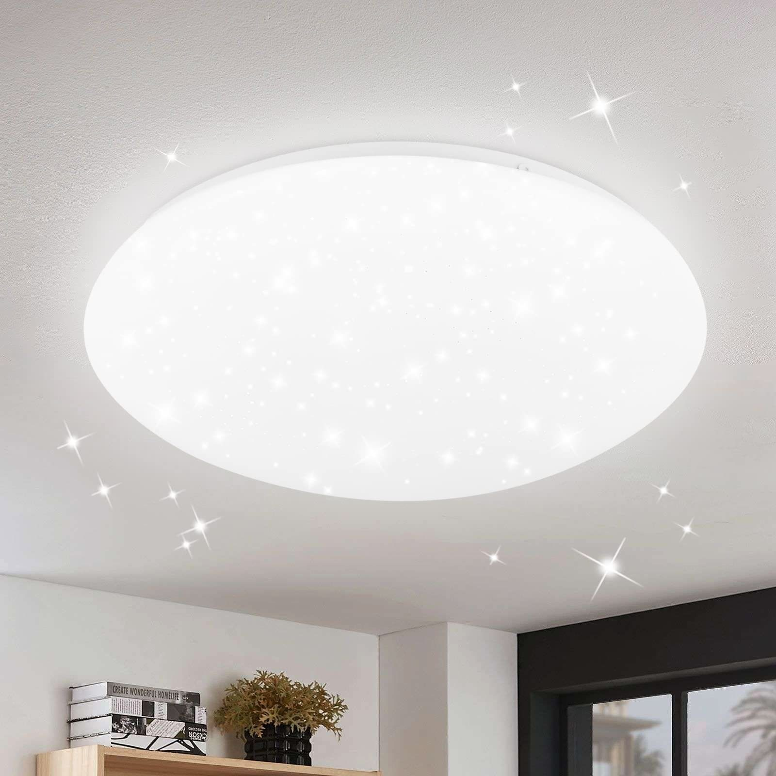 Deckenleuchte mit sternförmigen Lichtern. Weiße Decke, schwarzer Akzent an der Wand.