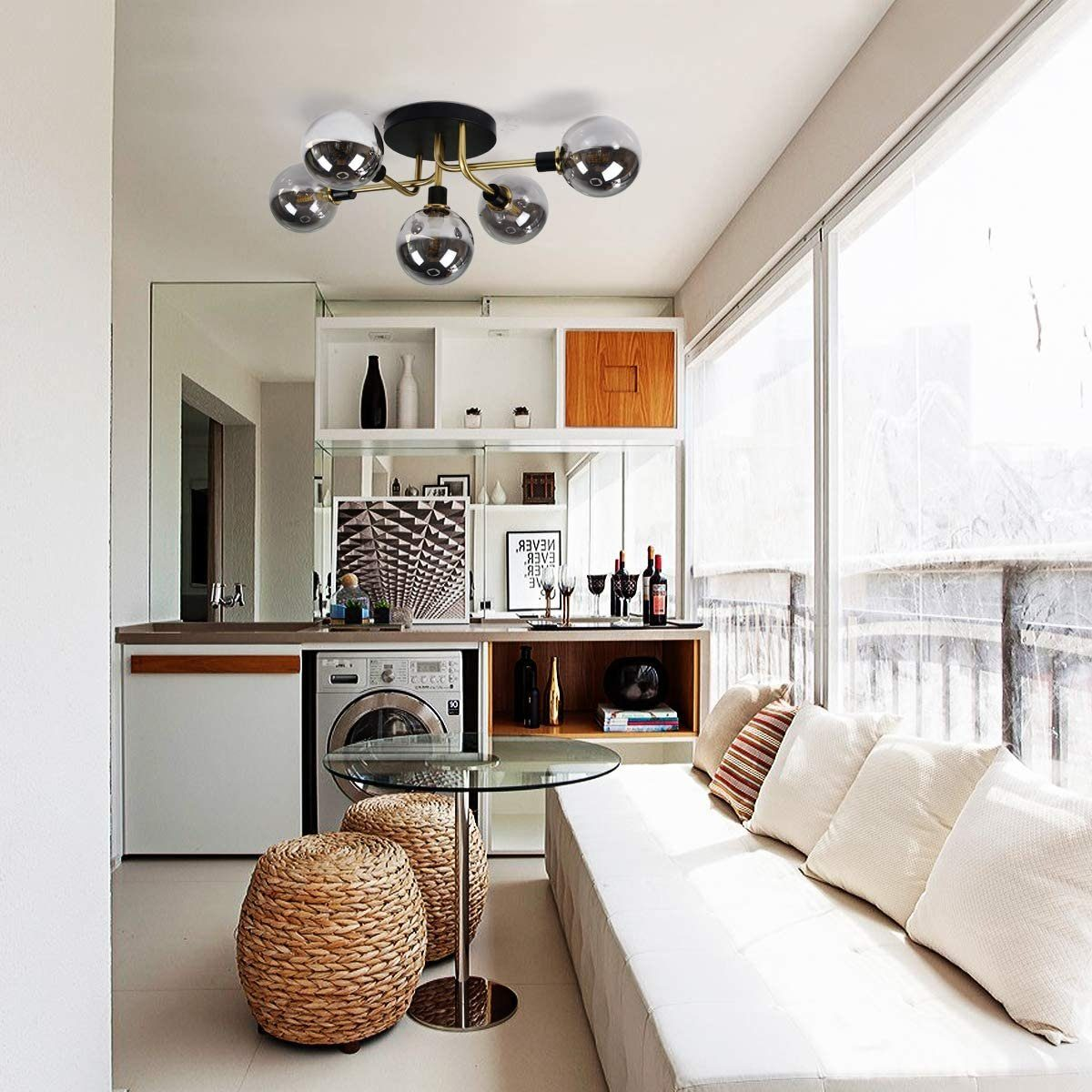 Innenraum mit weißem Sofa, Glastisch und moderner Deckenleuchte mit mehreren Glaskugeln.