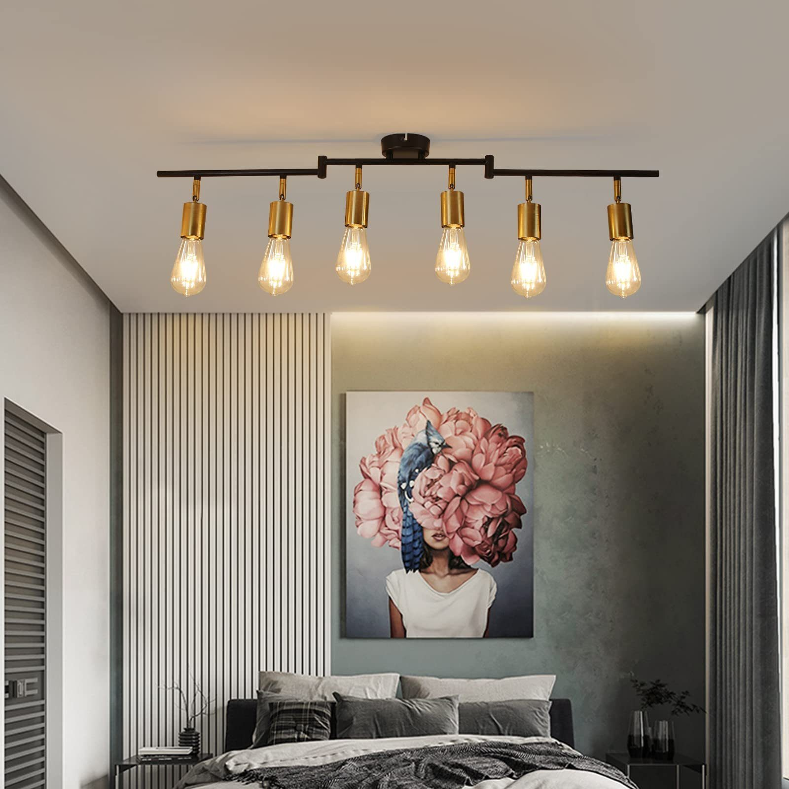 Sypialnia z obrazem kobiety. Jest łóżko i lampa z sześcioma żarówkami.