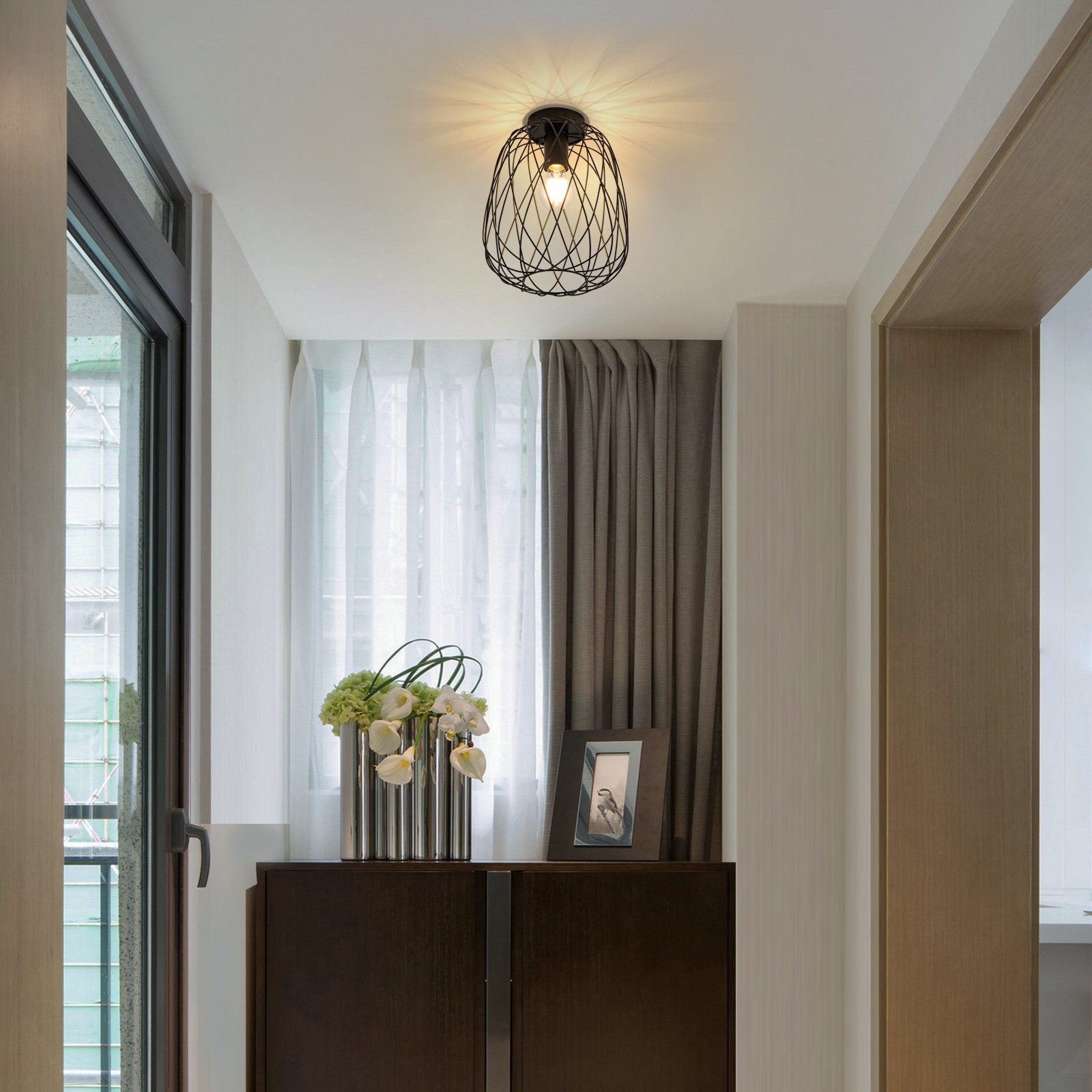 Corridoio con lampada a soffitto, mobile con fiori e un quadro incorniciato.