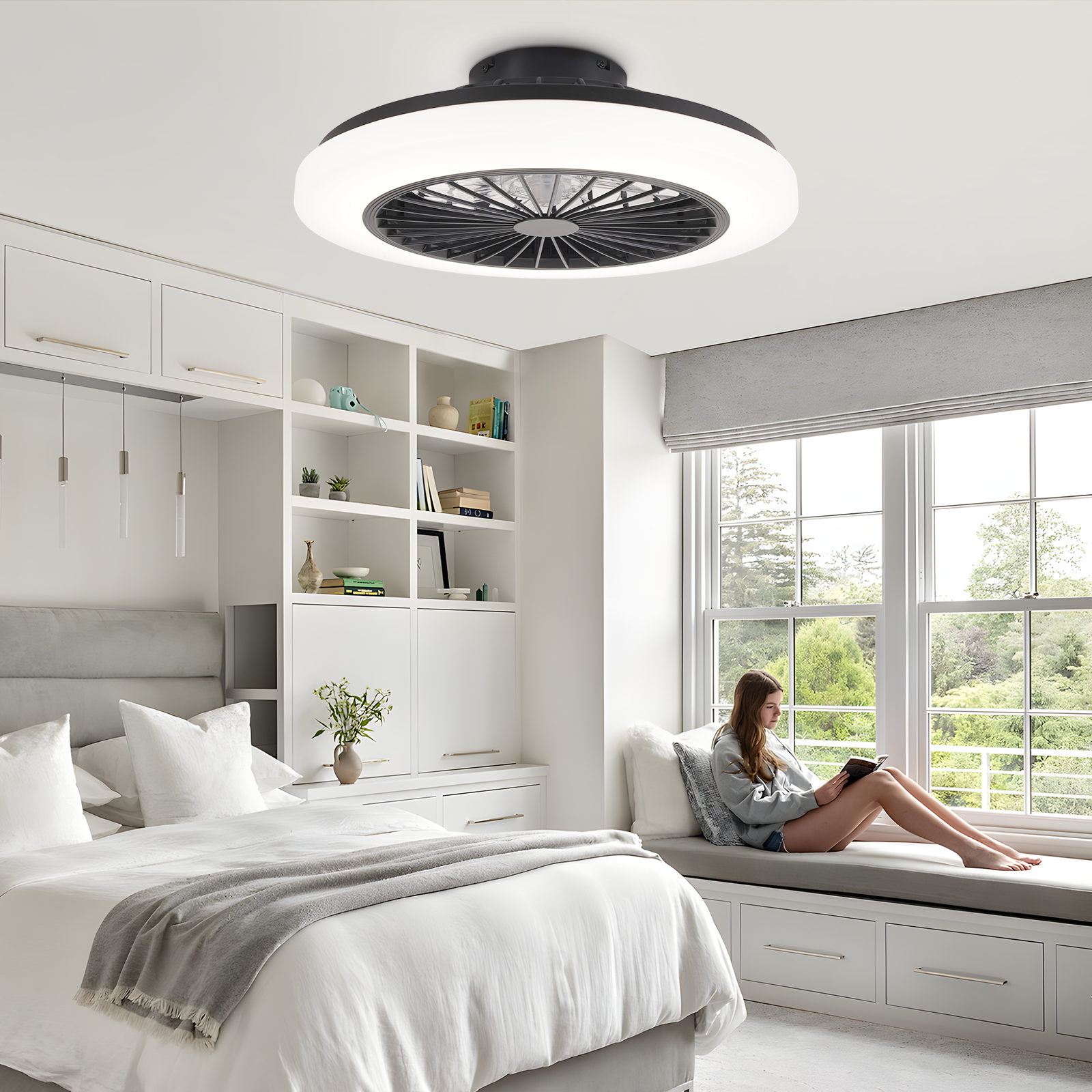 Sypialnia z wentylatorem sufitowym, kobieta czytająca na parapecie, biało-szara kolorystyka.