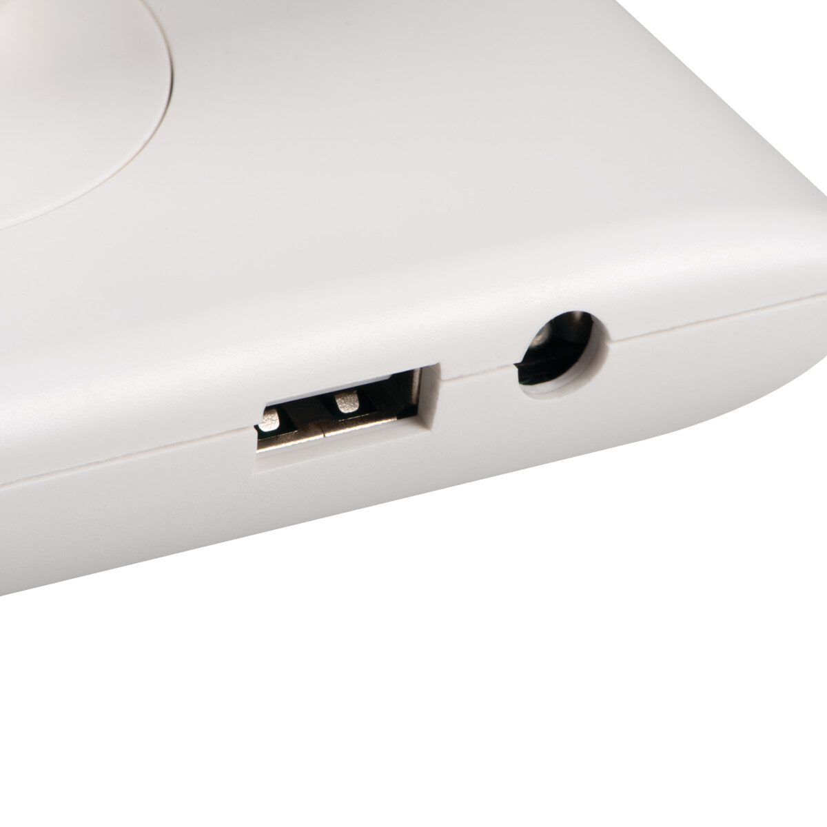 Primer plano de superficie blanca con puerto USB y un pequeño orificio redondo.