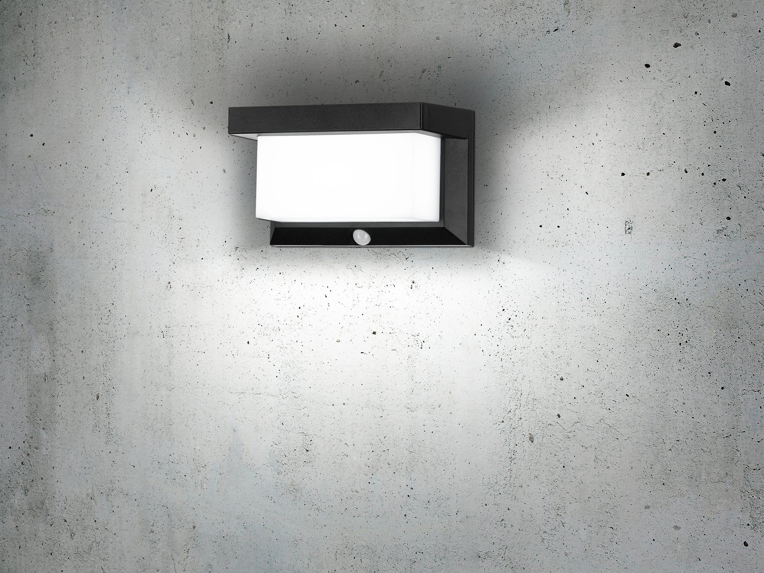 Una lámpara de pared negra con una superficie emisora ​​de luz blanca.