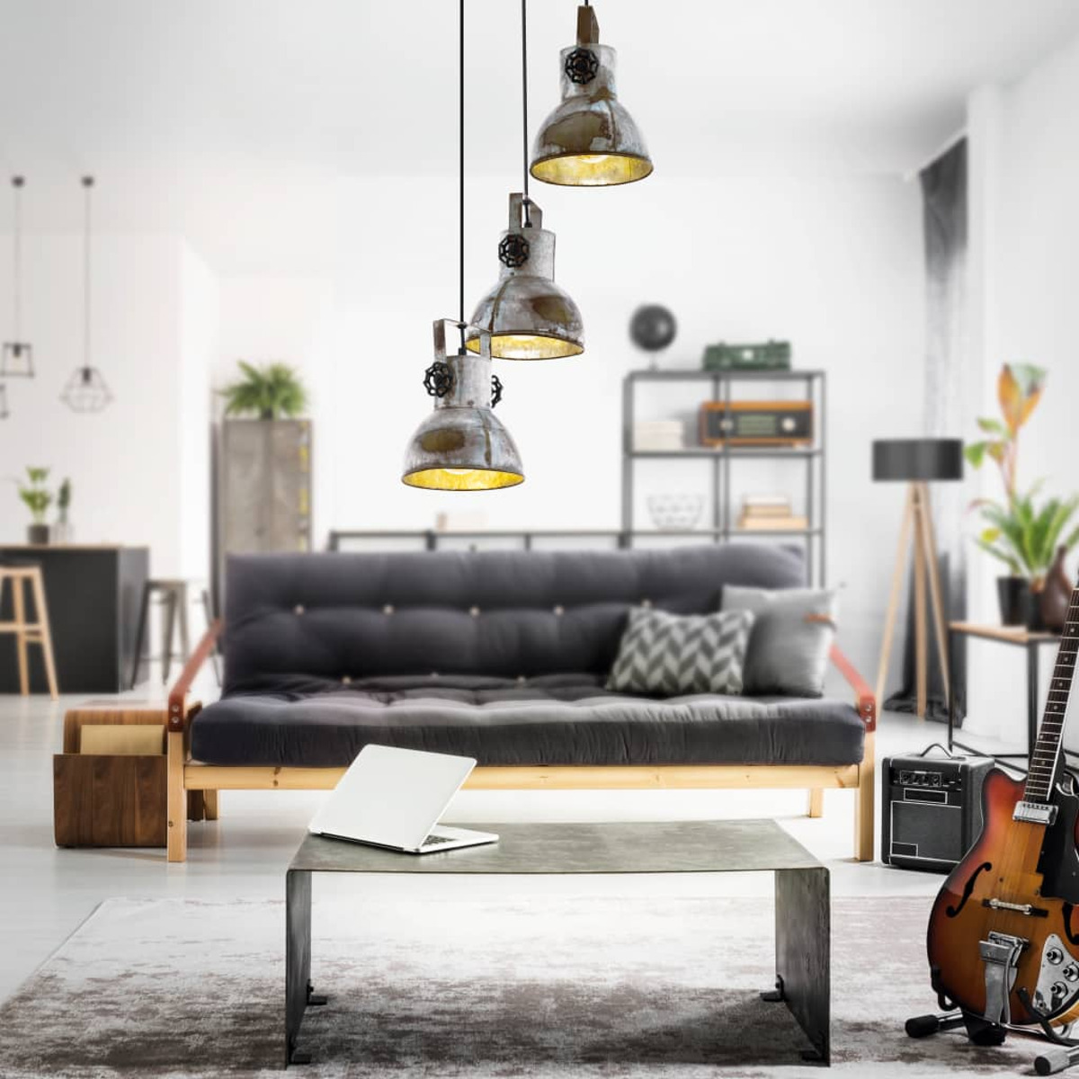 Wohnzimmer mit drei Pendelleuchten, Sofa, Tisch, Gitarre und Laptop. Weiße Wände.