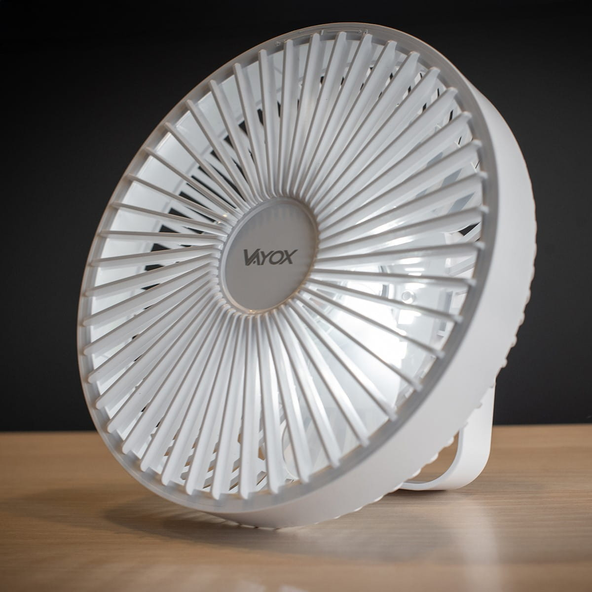 Biały wentylator z wieloma łopatkami na ciemnym tle.
