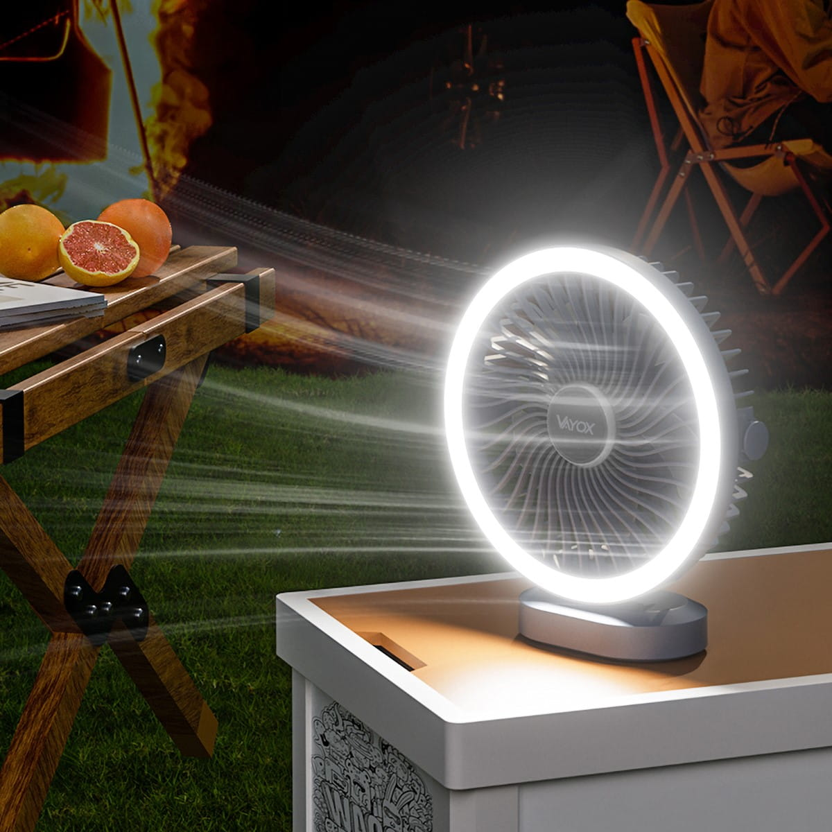 Szary wentylator z okrągłym światłem LED na stole. Na stole pomarańcze i grejpfruty.