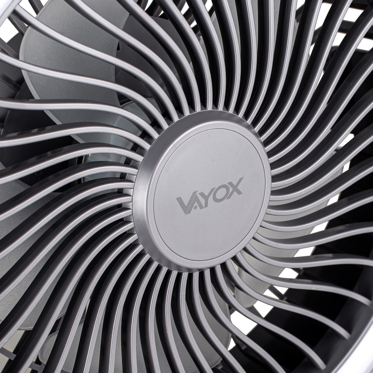 Zbliżenie szarego wentylatora. Wentylator ma wiele zakrzywionych łopatek wychodzących z centralnej piasty.