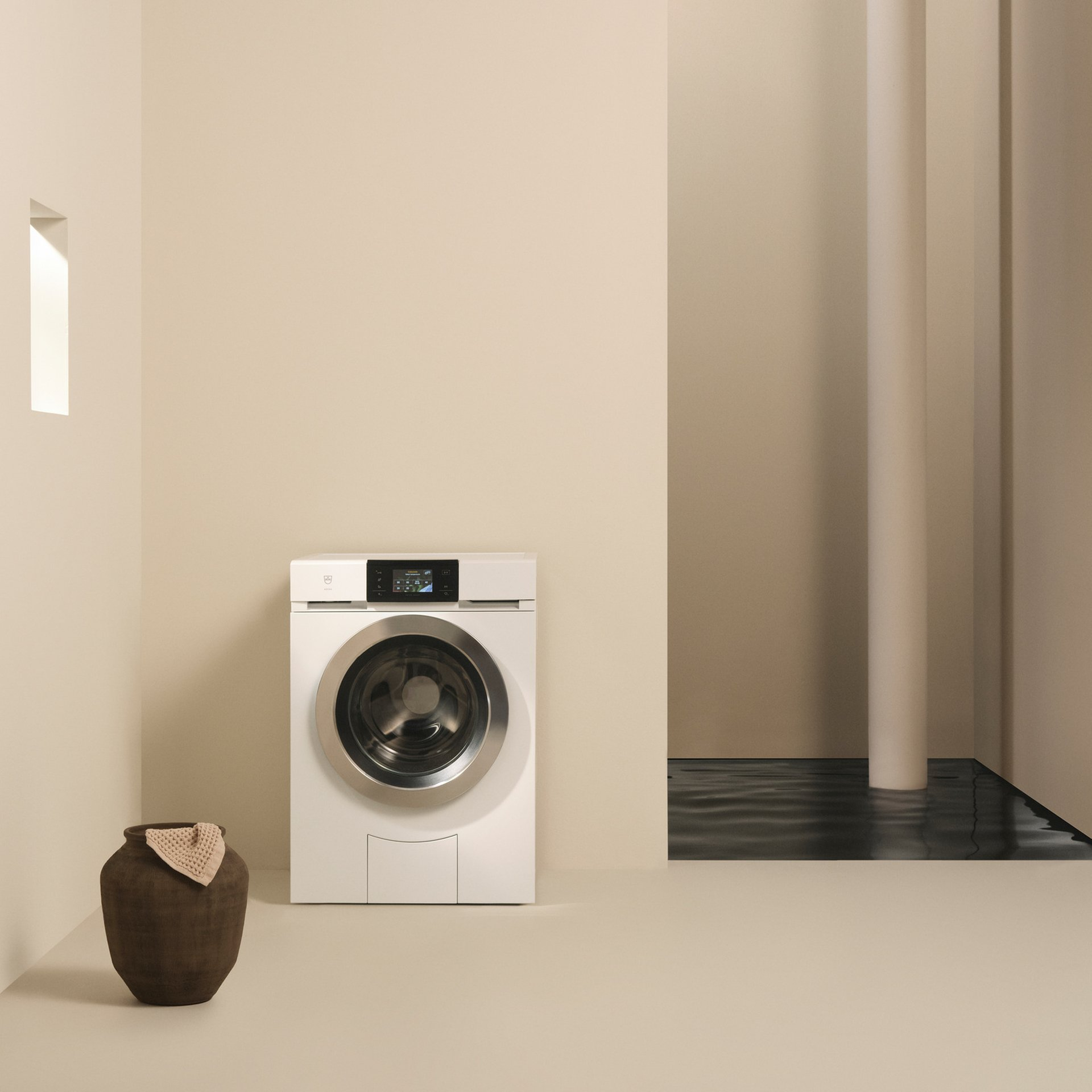 Una lavatrice in una stanza beige. Un vaso e un tappeto di fronte.