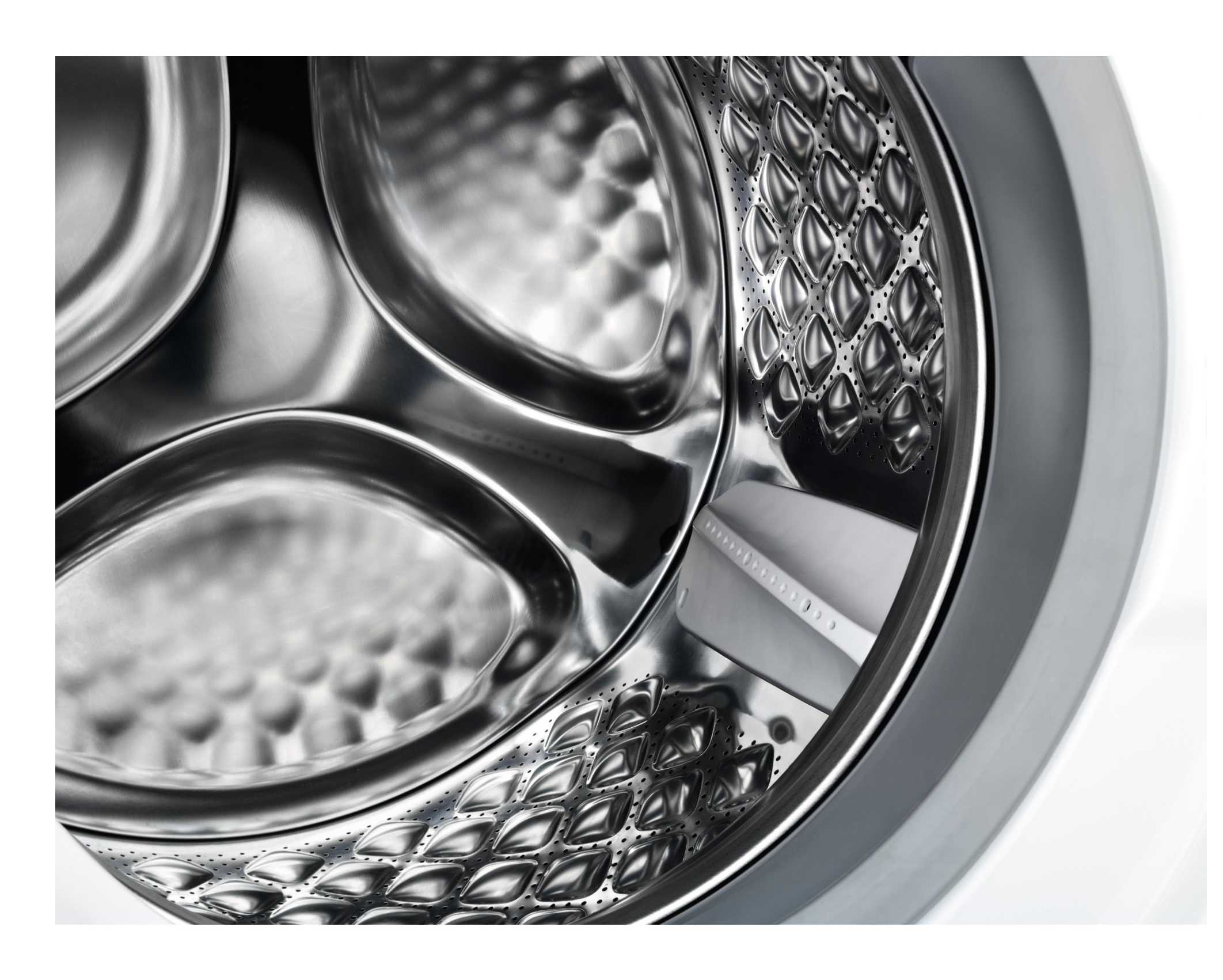 Wewnątrz bębna pralki, błyszczące wnętrze ze stali nierdzewnej o wzorze plastra miodu.