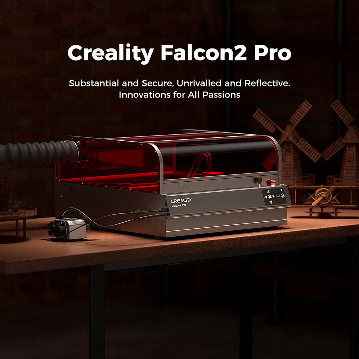Grawer laserowy Creality Falcon2 Pro na drewnianym stole. Jest czerwony i srebrny, z tekstem.