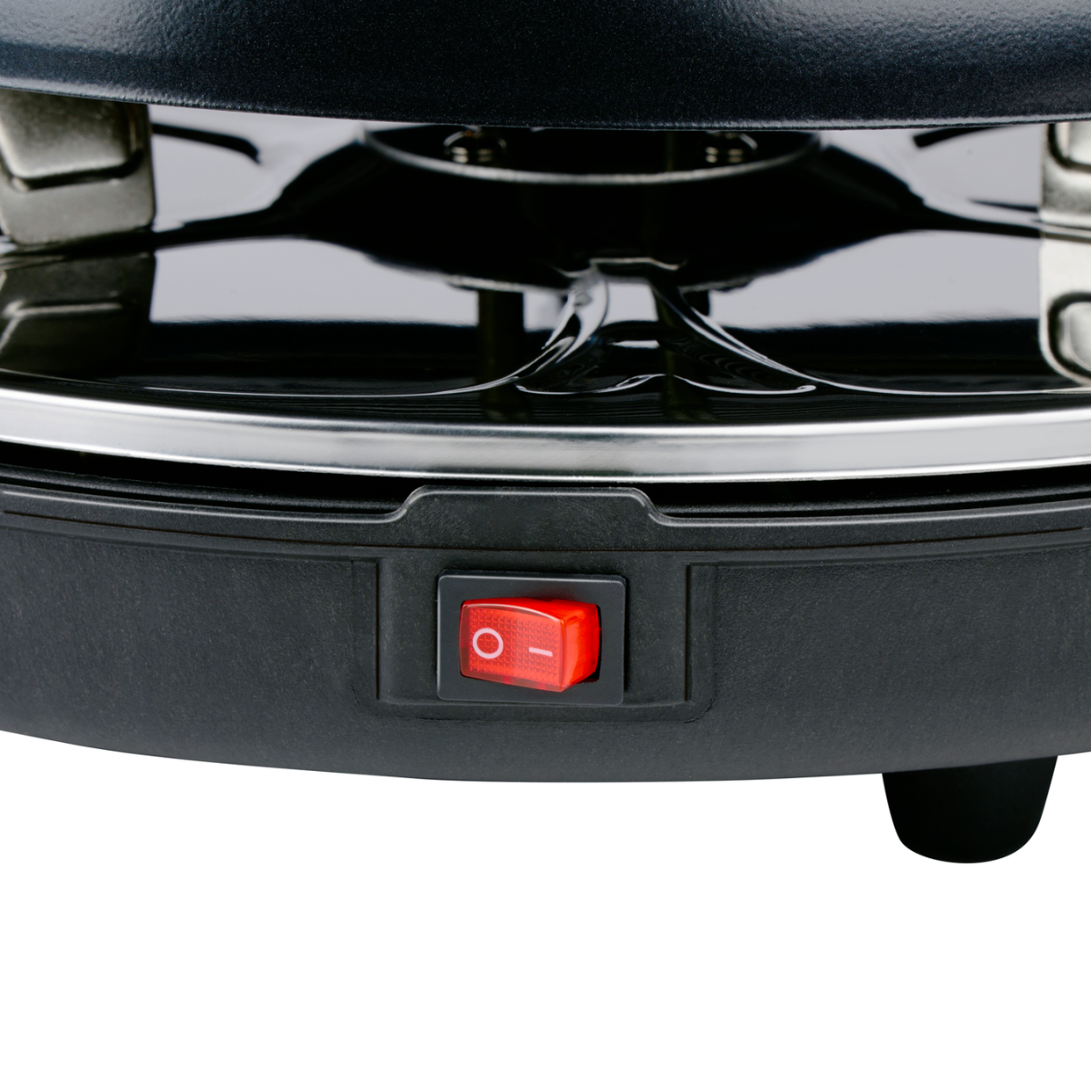Nahaufnahme des roten Netzschalters eines schwarzen Raclette-Grills auf schwarzem Untergrund.