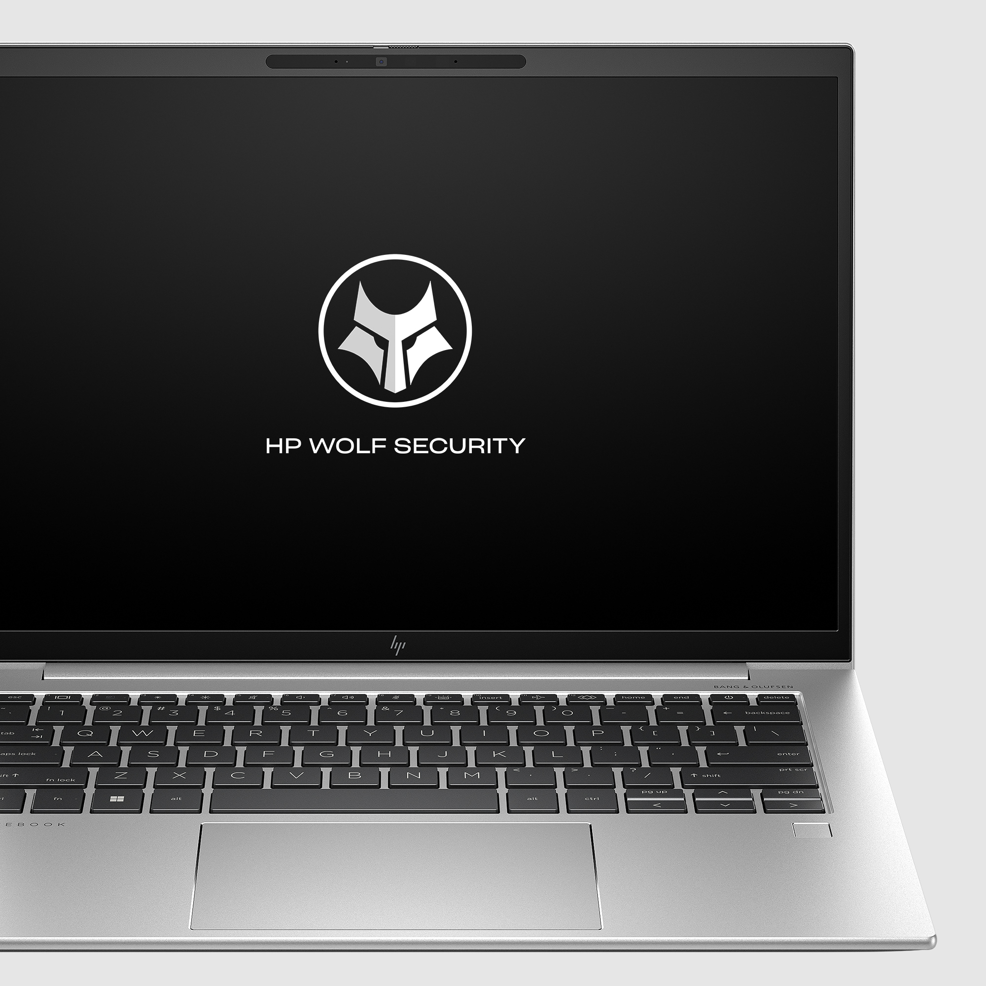 Srebrny laptop otwarty, widok z boku, pokazujący klawiaturę i ekran z logo HP Wolf Security na czarnym tle.
