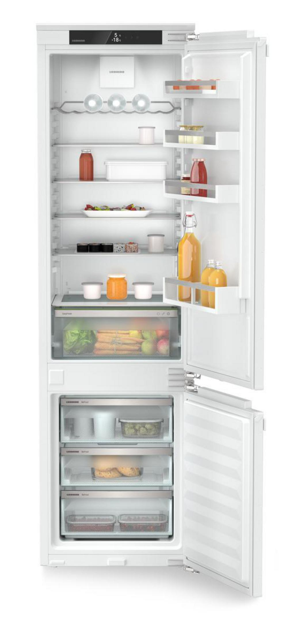 Refrigerador blanco con comida dentro, con las puertas abiertas. Hay estantes y cajones.