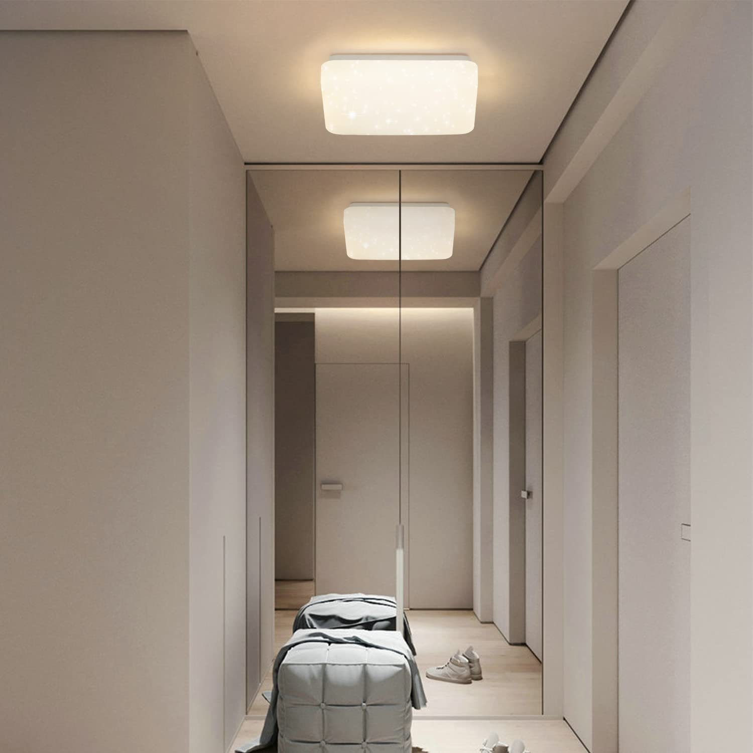 Korytarz z lustrem, oświetleniem sufitowym i ławką z kocem i butami.