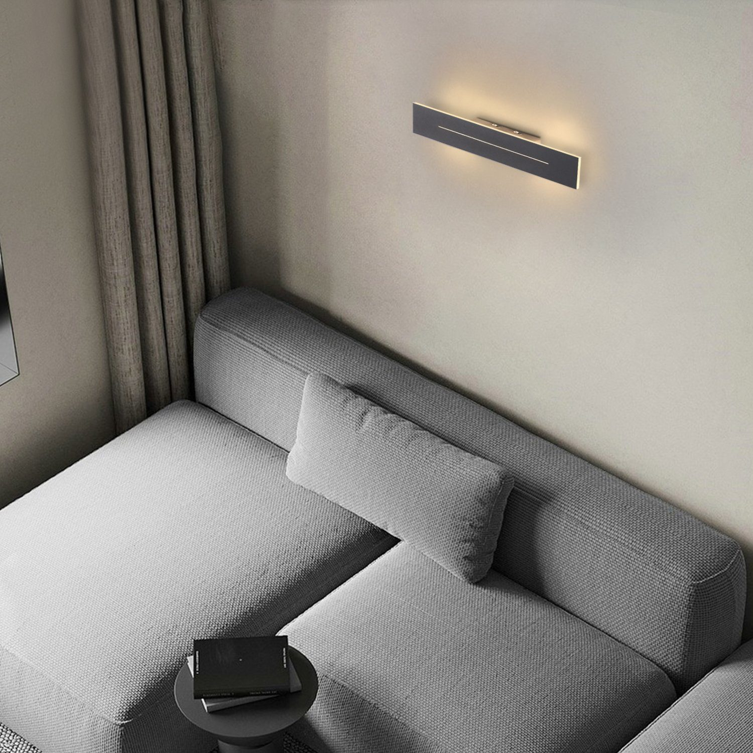 Interni moderni. Divano grigio con cuscino rettangolare. Applique nero che emette luce calda.