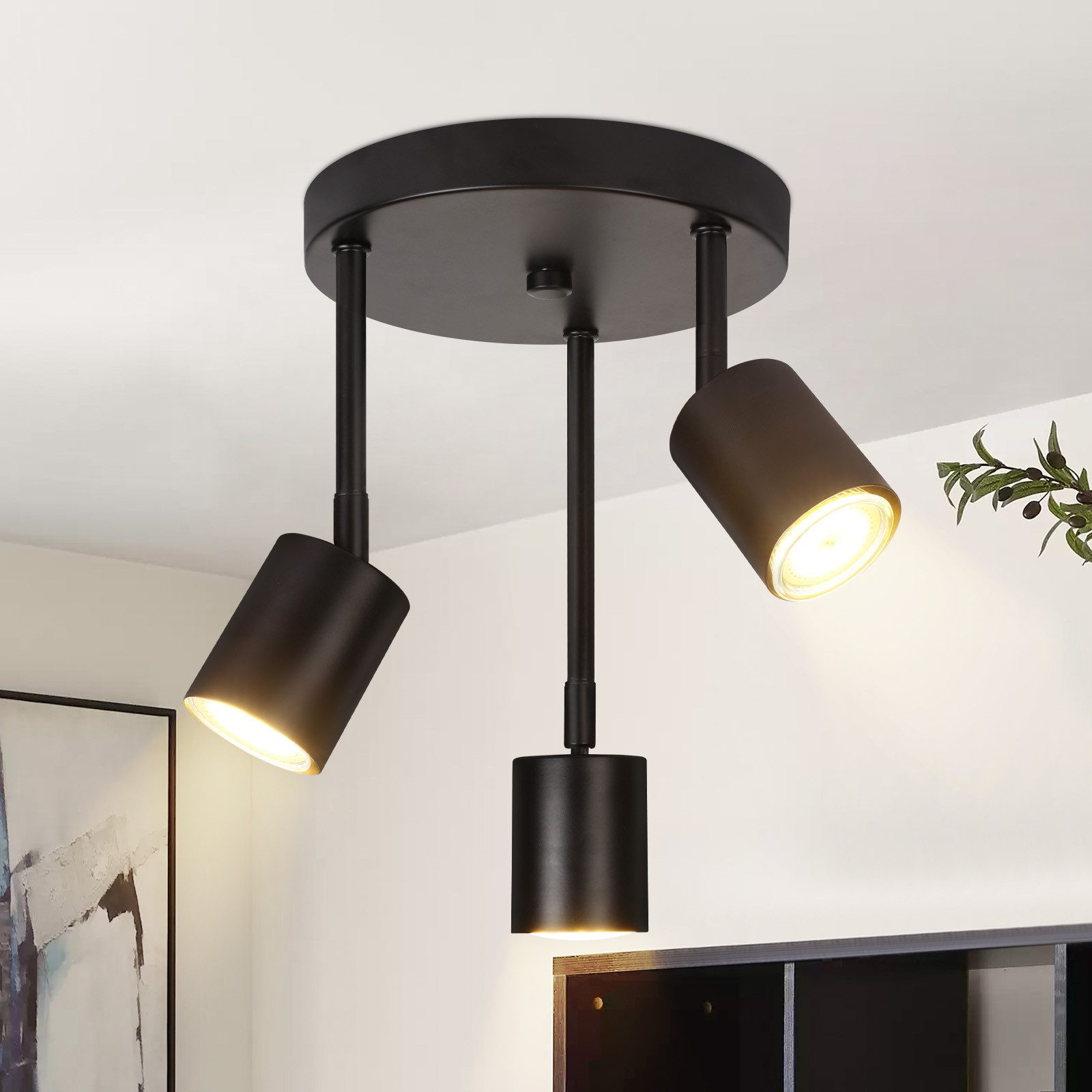 Tre faretti neri montati a soffitto, che illuminano la stanza.